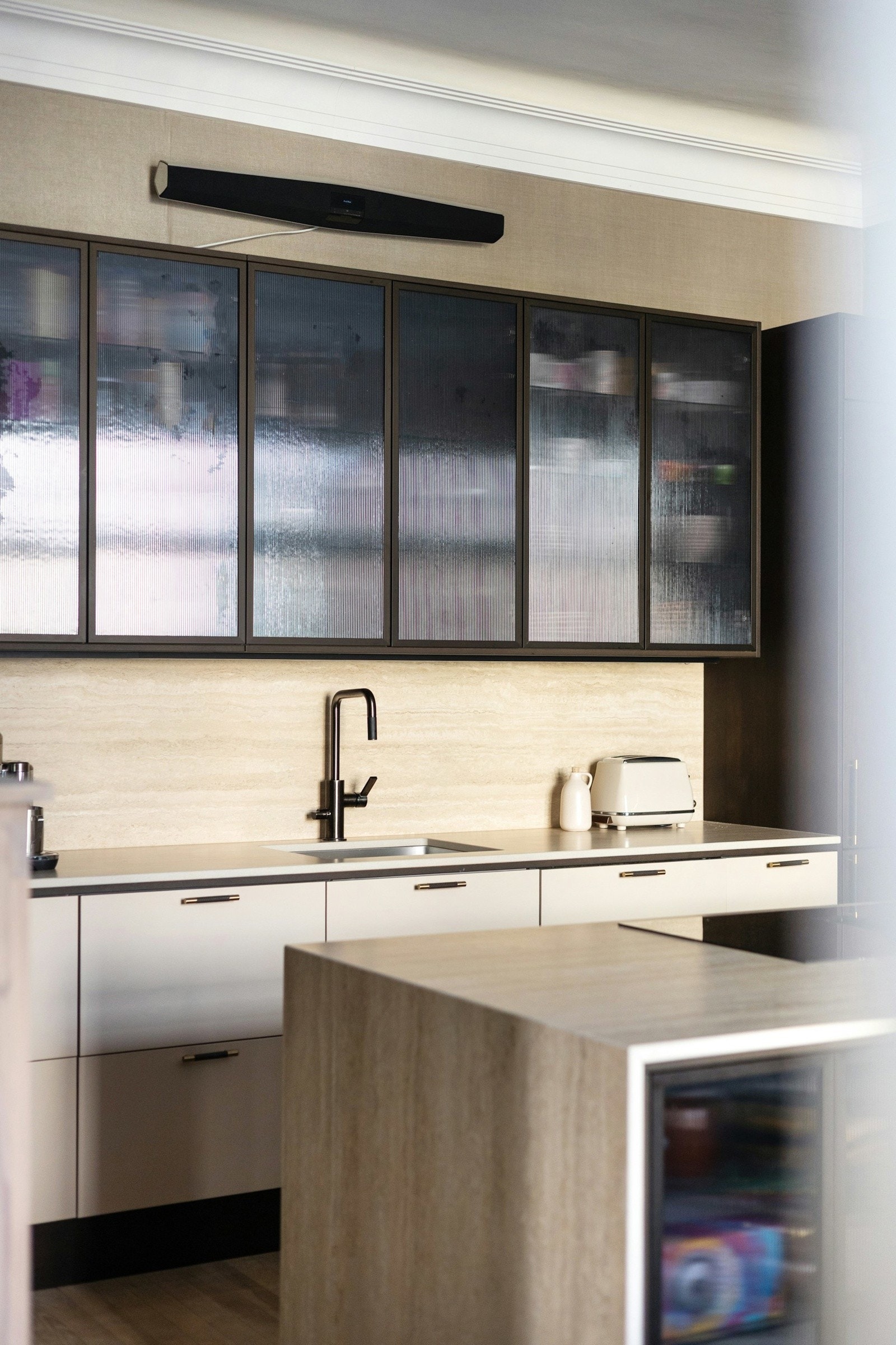 De elegante glasshyllene langs veggen tilfører både oppbevaringsmuligheter og en eksklusiv følelse. Galleribilde