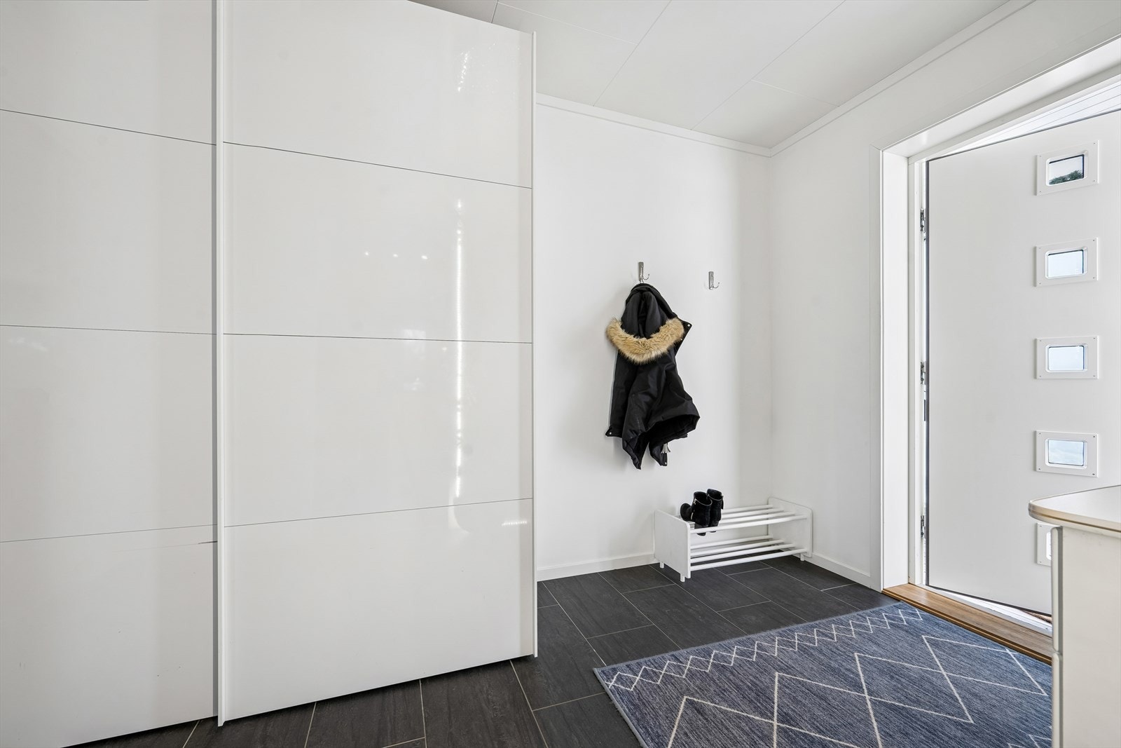 Innbydende entré med flislagt gulv og god plass til oppbevaring i skyvedørsgarderobe. Galleribilde