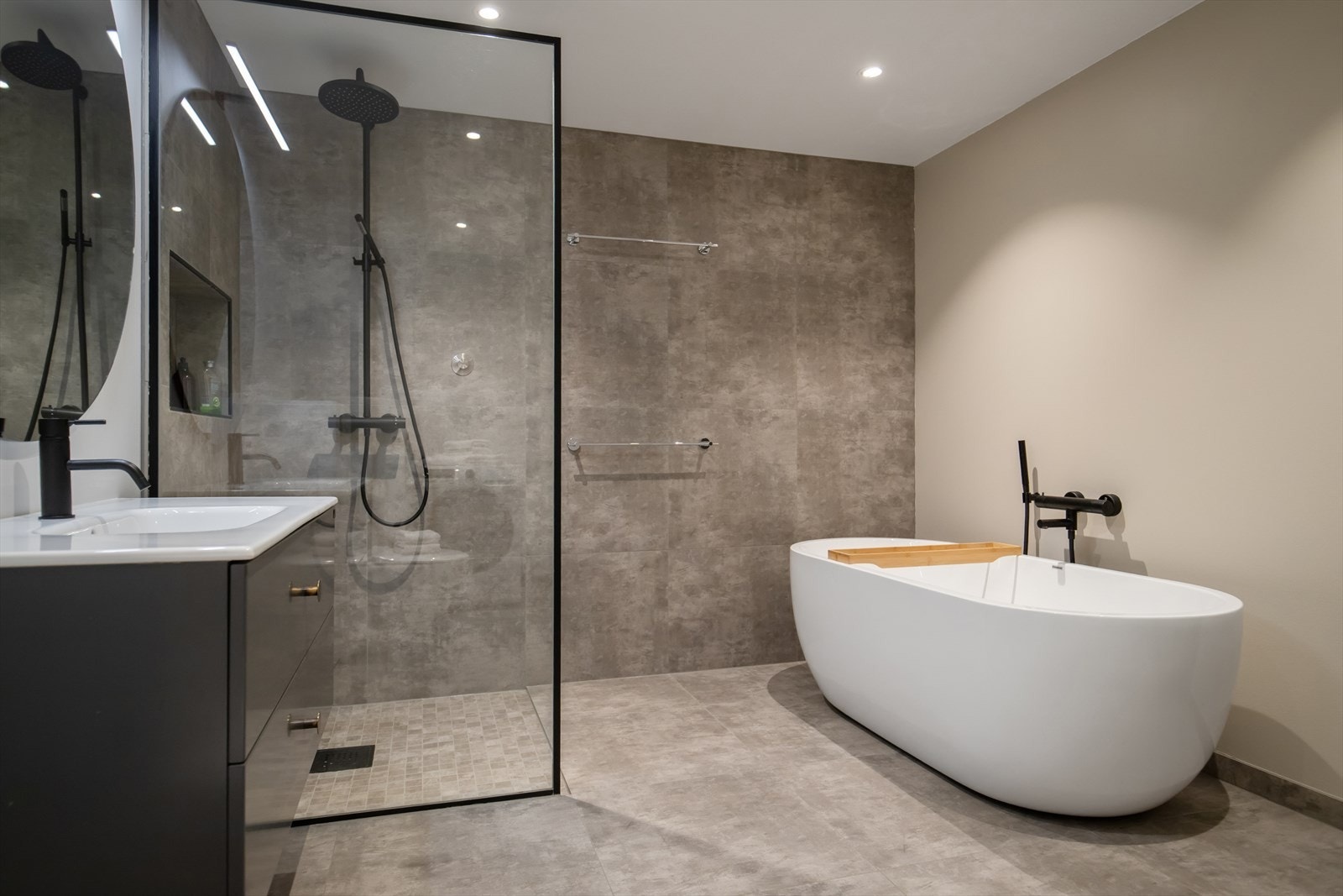 Baderommet er innredet med nedfelt servant, dusjhjørne med glassvegger, vegghengt toalett, badekar og plass for vaskemaskin. Galleribilde