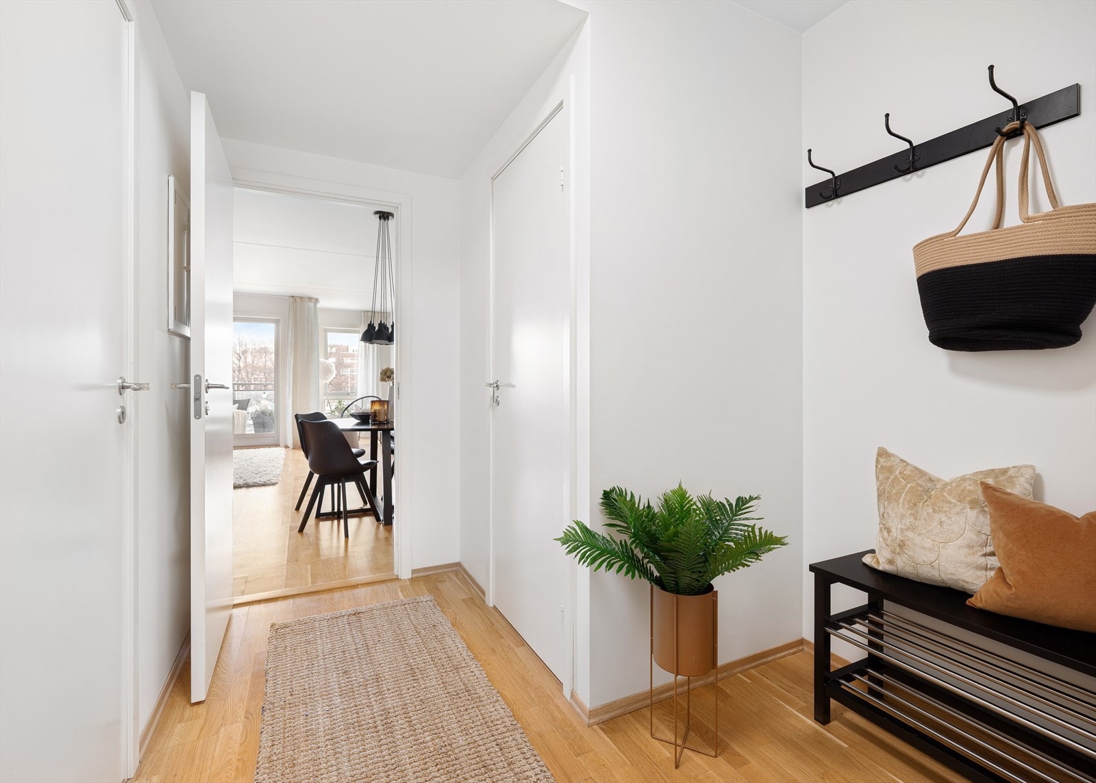 Lys og innbydende entré. Praktiske løsninger for oppbevaring av yttertøy og sko, med knagger på vegg og plass til benk eller skohylle Galleribilde