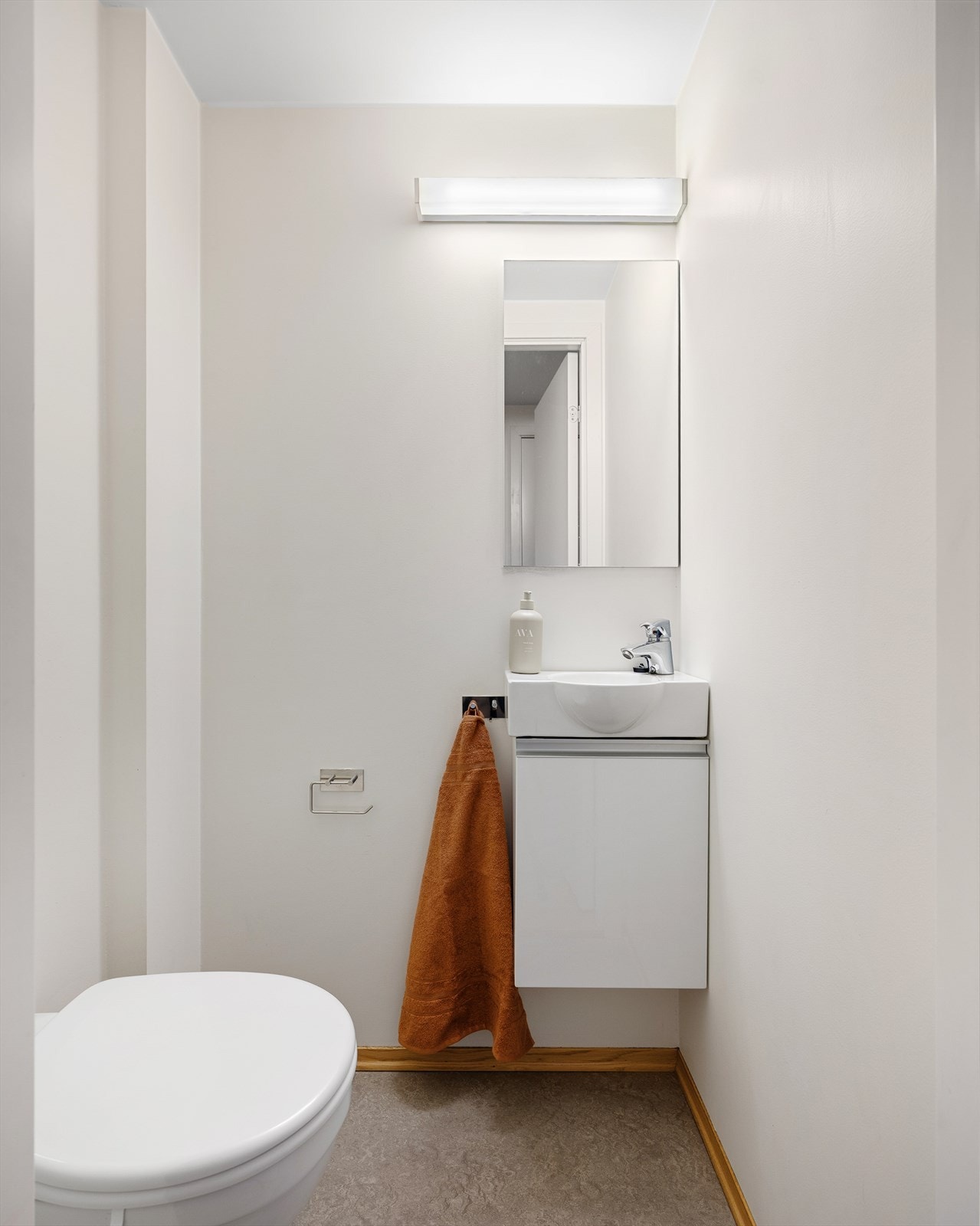 Toalettrom med vegghengt toalett, servant med innredning og skapdør for praktisk oppbevaring Galleribilde