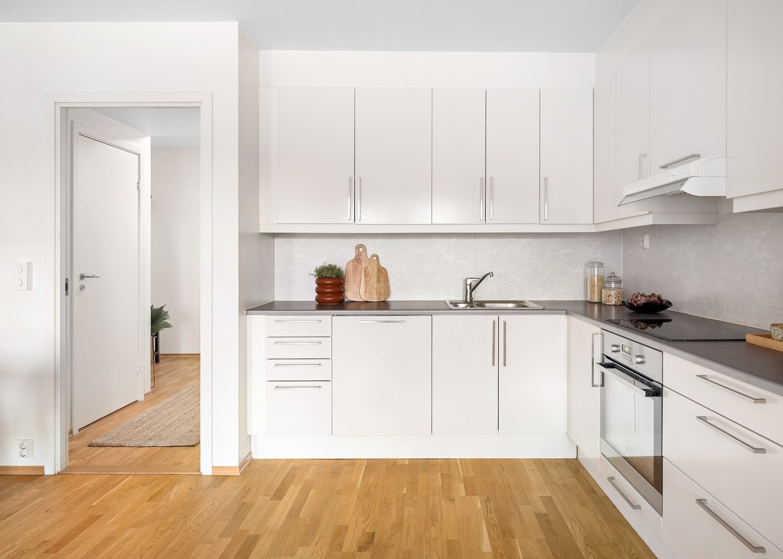 Lyst og funksjonelt kjøkken med tidløs, hvit innredning og gode oppbevaringsmuligheter i både skap og skuffer Galleribilde