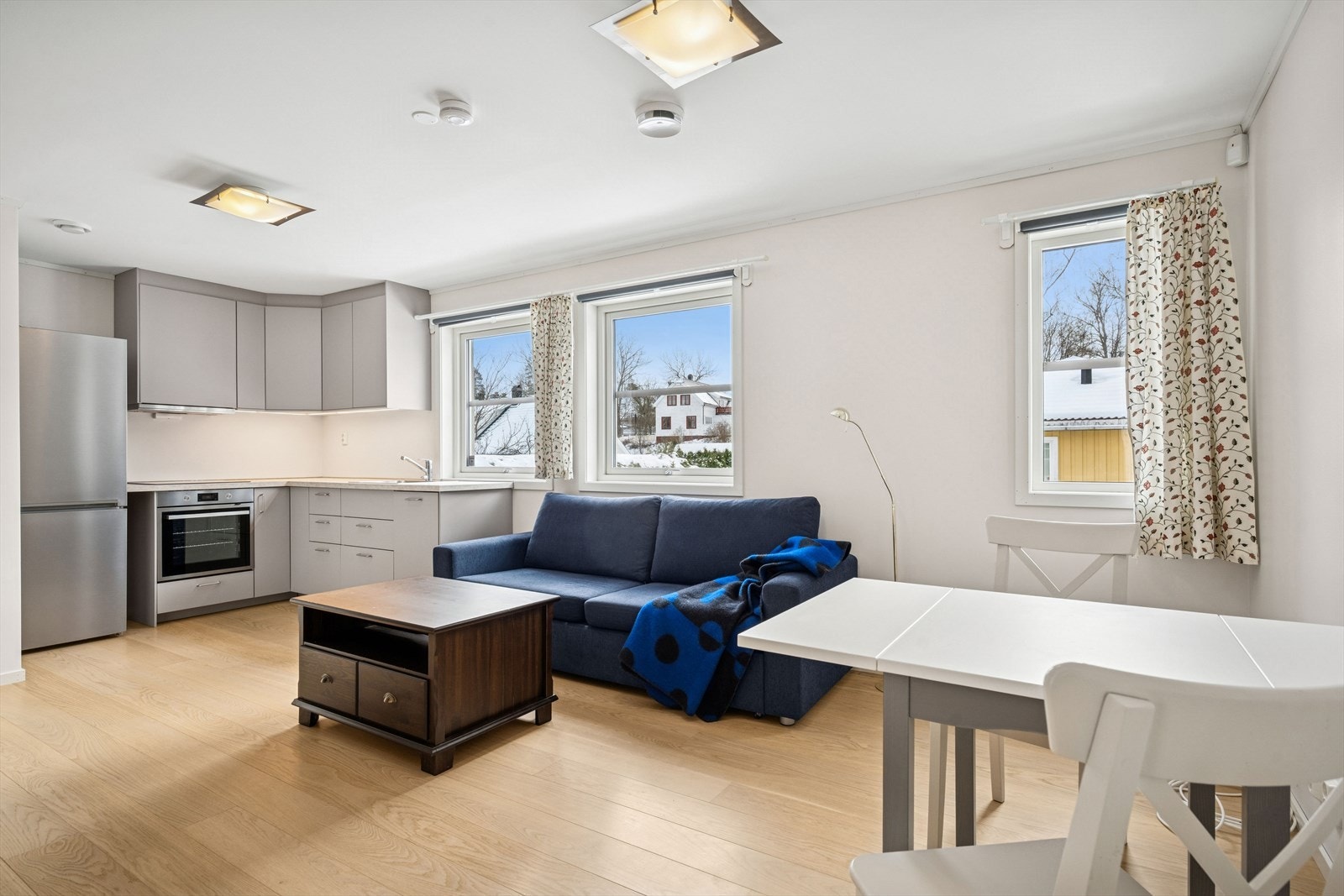 Hybelens oppholdsrom har en åpen løsning mellom stue og kjøkken. Kjøkkenet er innredet med glatte fronter og integrerte hvitevarer. Galleribilde