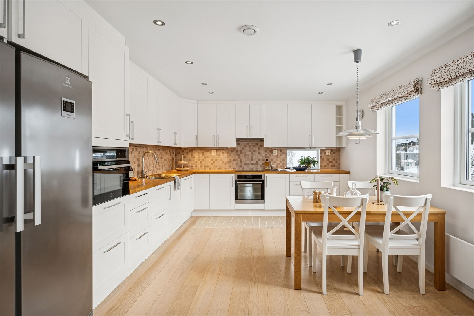 Kjøkkenet er innredet med hvite fronter og heltre benkeplate som gir et tidløst og gjennomført uttrykk. Galleribilde