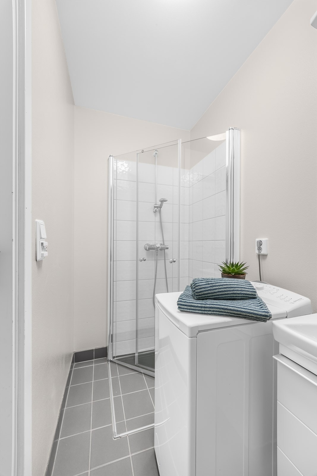 Badet er innredet med toalett, dusjhjørne med vegger og servant nedfelt i skap. Det er opplegg for vaskemaskin. Galleribilde