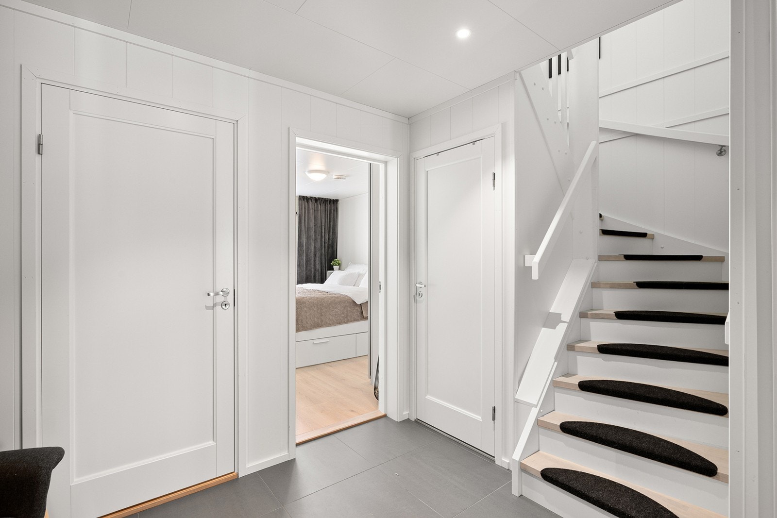 Praktisk bod under trappen gir ekstra oppbevaringsplass. Trapp med lyse materialvalg og mørke trinnbeskyttere leder videre til boligens øvrige etasje. Galleribilde