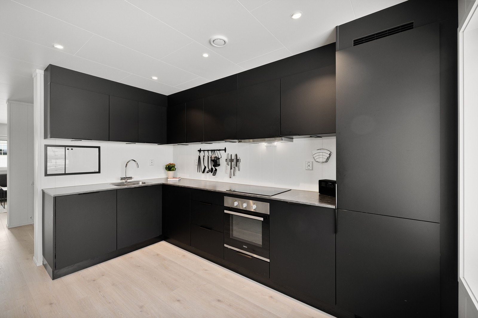 Kjøkkenet har en moderne og stilren innredning i mørke, slette fronter med god skap- og benkeplass. Galleribilde