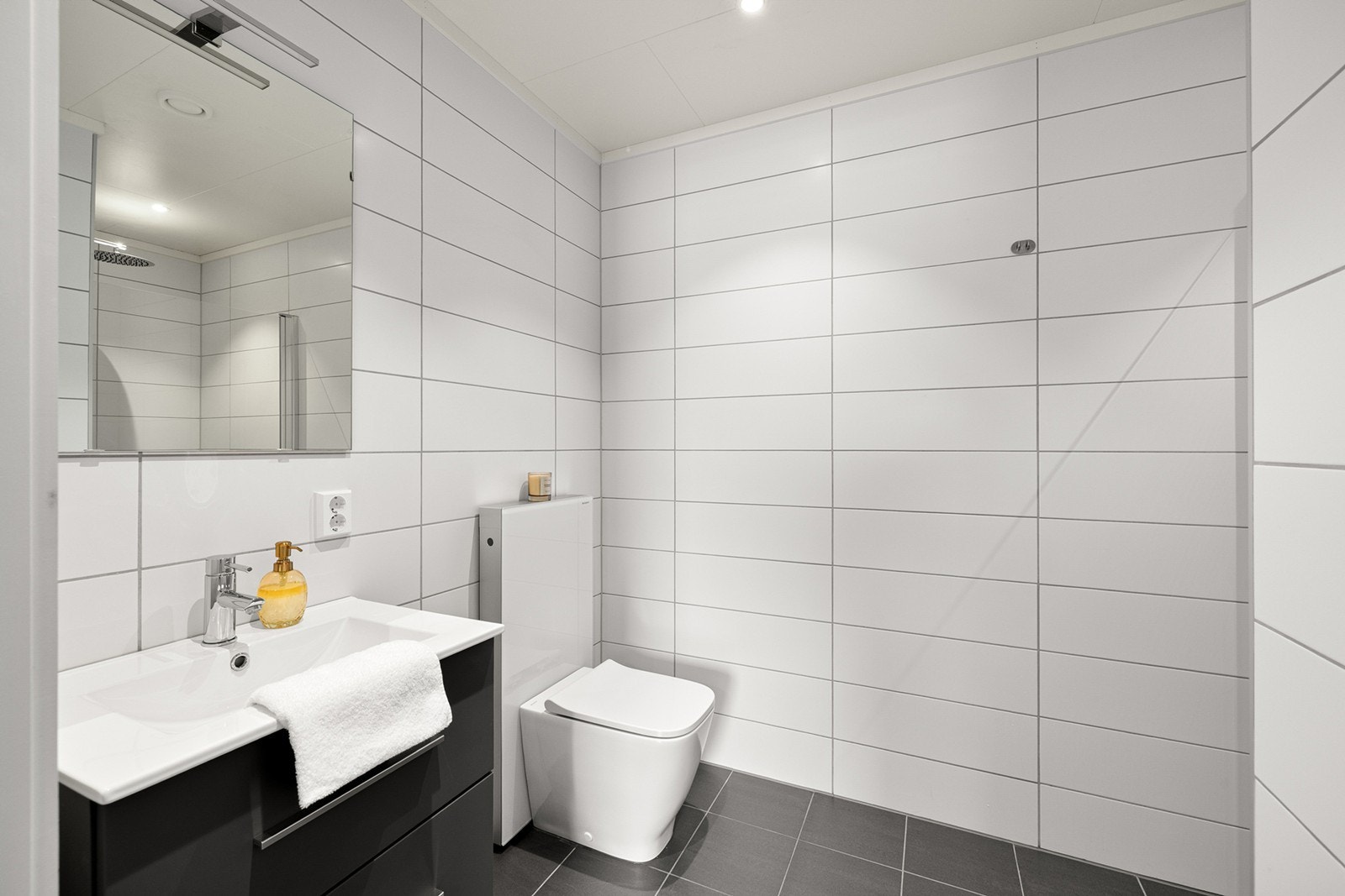 Flislagt og stilrent bad med moderne uttrykk og behagelig gulvvarme. Galleribilde