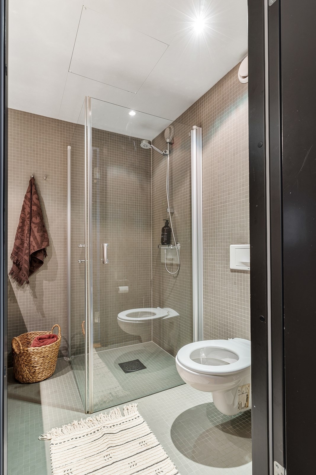 Dusjhjørne med innfellbare glassvegger og veggmontert WC for et stilrent uttrykk. Galleribilde