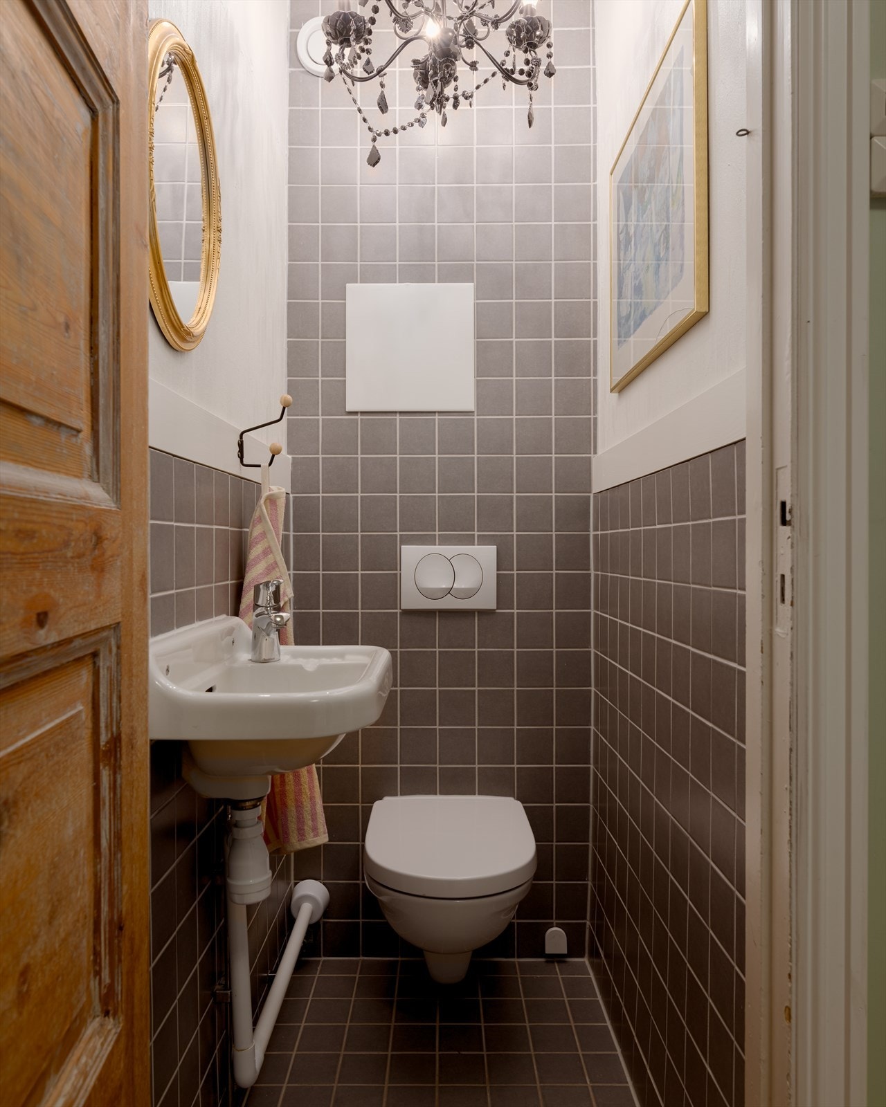 Separat toalettrom i samme stil som badet, med flislagte gulv og vegger. Rommet er utstyrt med servant og speil. Galleribilde