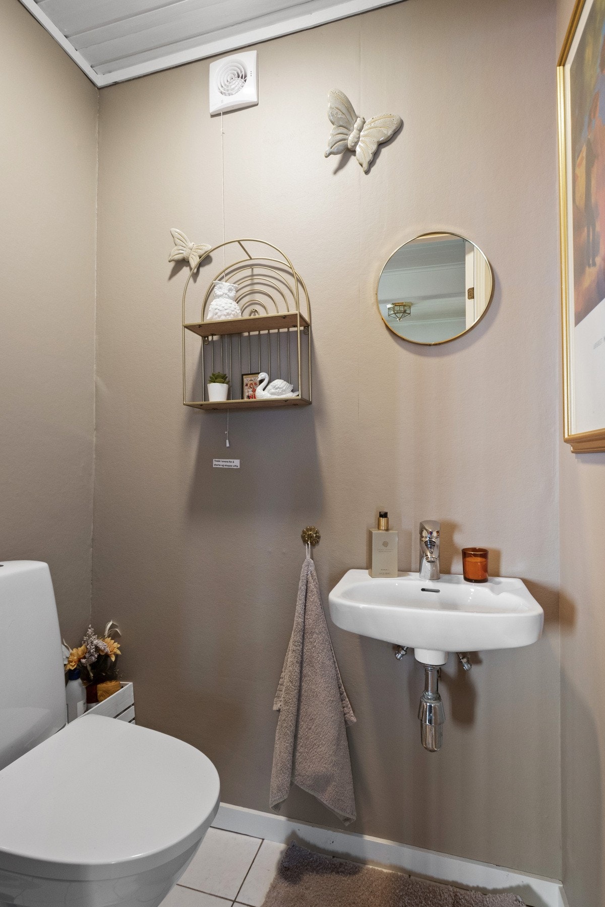 Wc-rommet har flislagt gulv, ny veggtapet og enkel servant i tillegg til toalett. Galleribilde