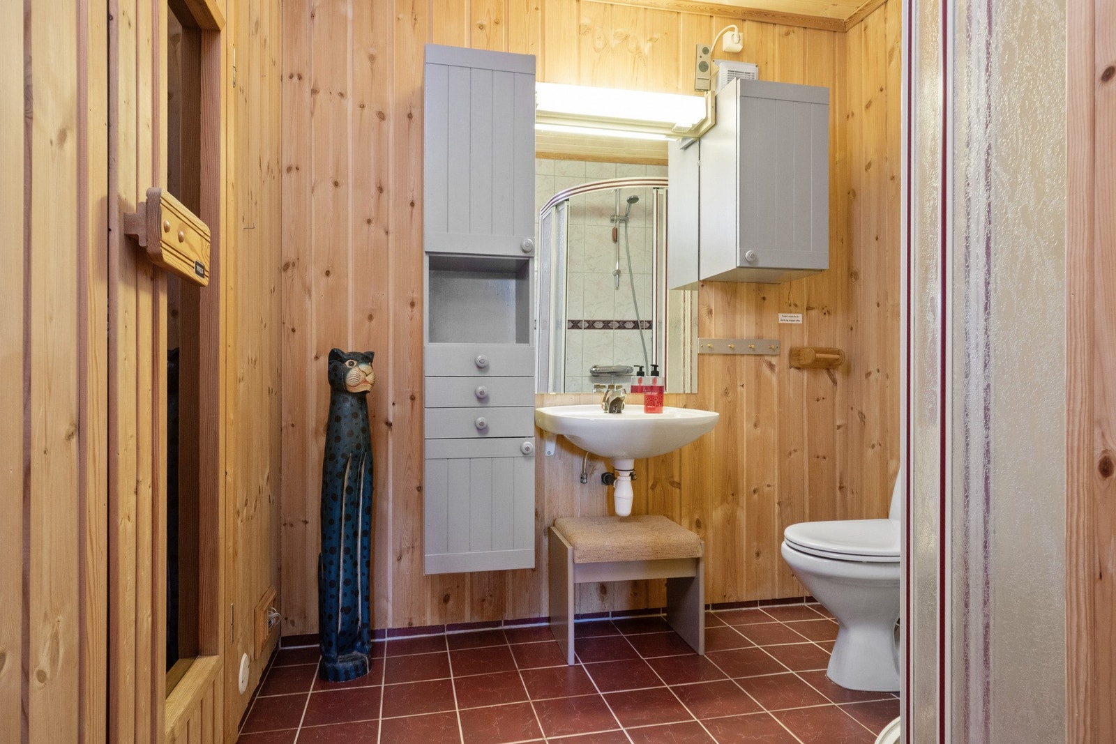 Badet er utstyrt med toalett, dusjhjørne med skyvedører og flislagt gulv med varmekabler. Galleribilde