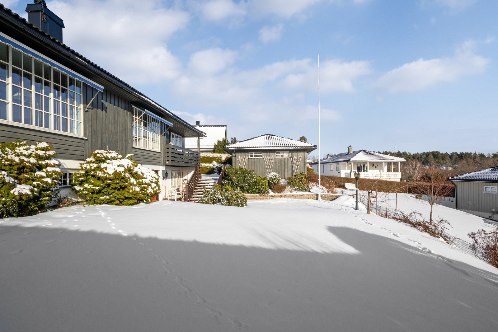Tomten er pent beplantet med blomster og omkranses av tujahekker mot sør og nord, samt plenarealer mot øst og vest. Galleribilde
