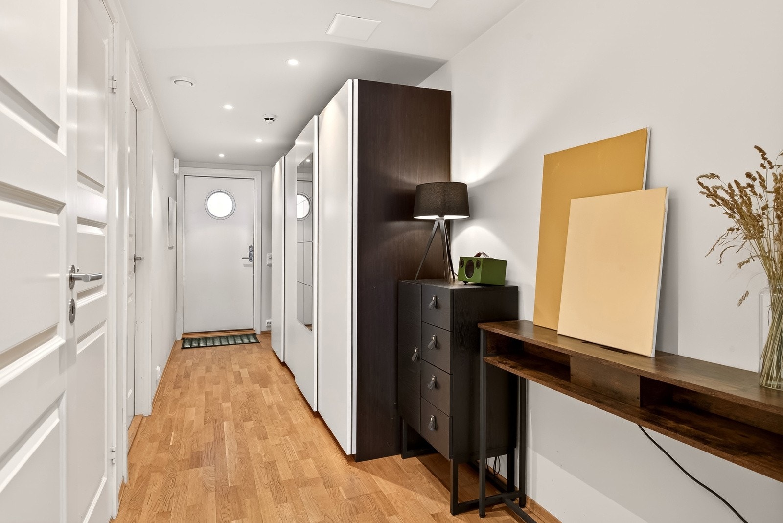 Gang og entré i lyse farger med parkett på gulv og matle flater. Her er det plass til å sette fra seg yttertøy og sko, samt garderobeskap for oppbevaring av yttertøy. Galleribilde