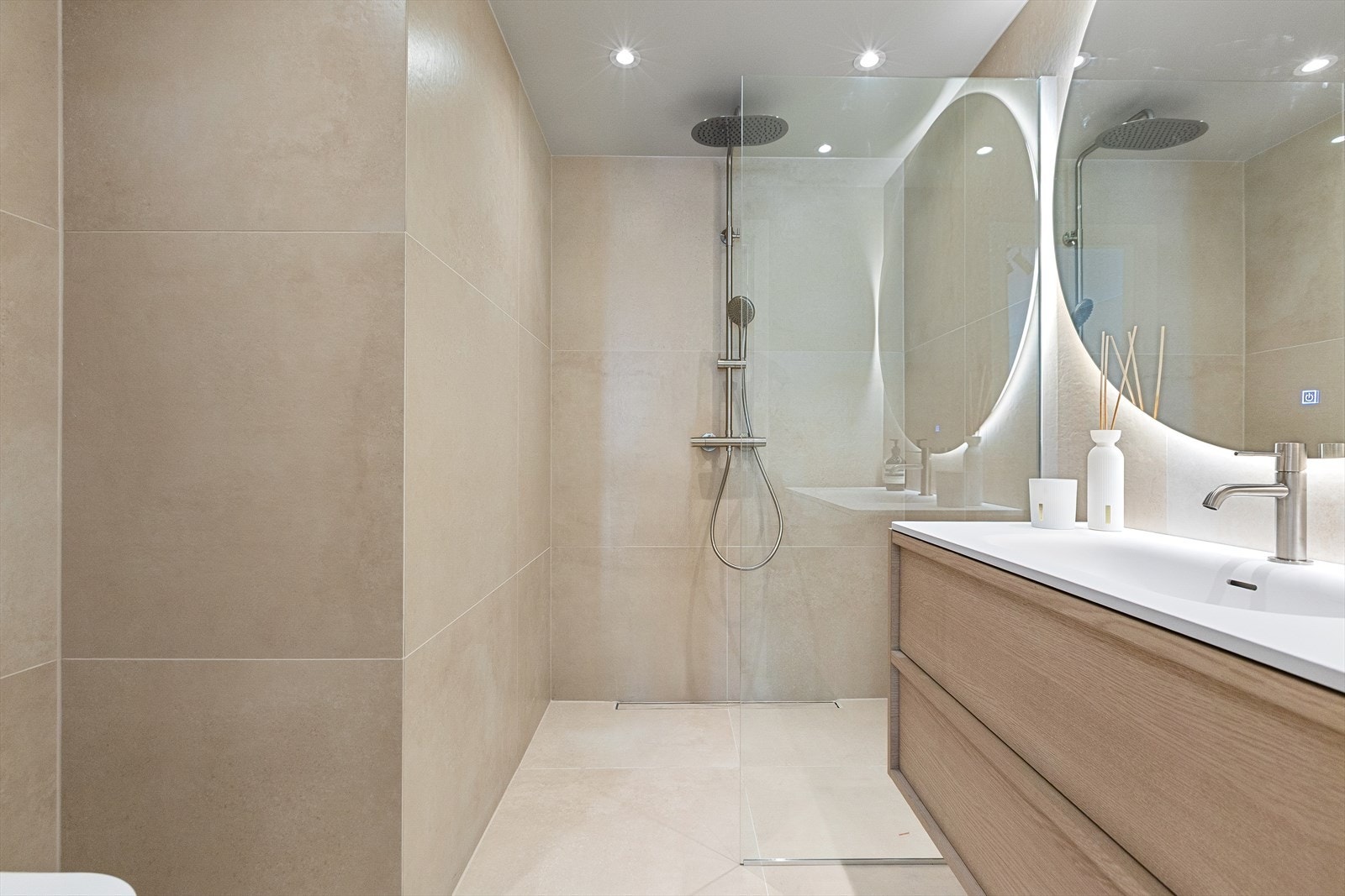 Romslig og eksklusivt bad med varmekabler i gulv og downlightsbelysning. Store fliser i 80x80 cm i samme fargetone på gulv og vegger gir et rolig og helhetlig uttrykk Galleribilde