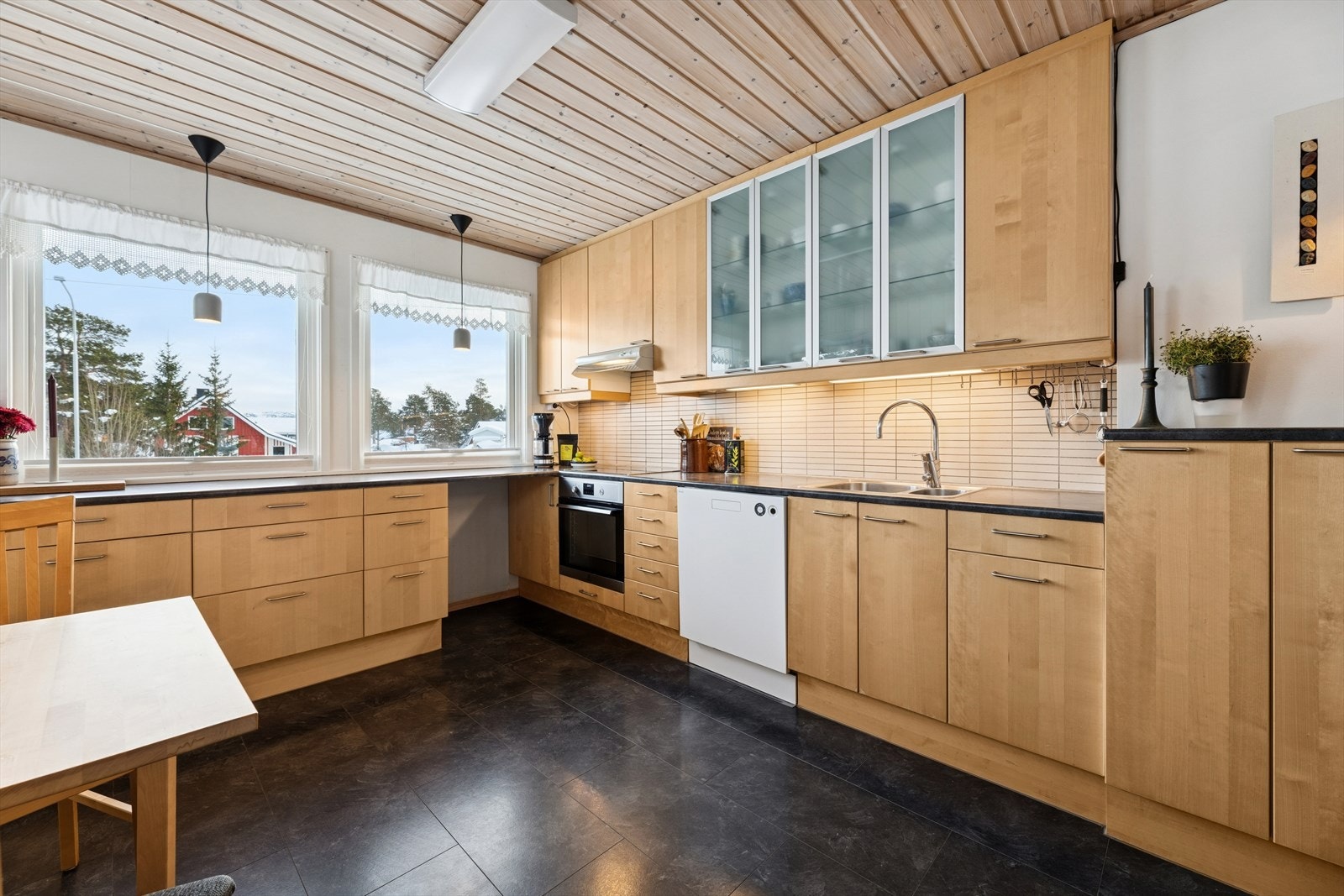 Det er belysning under overskapene og hvite fliser i benkeryggen. Galleribilde