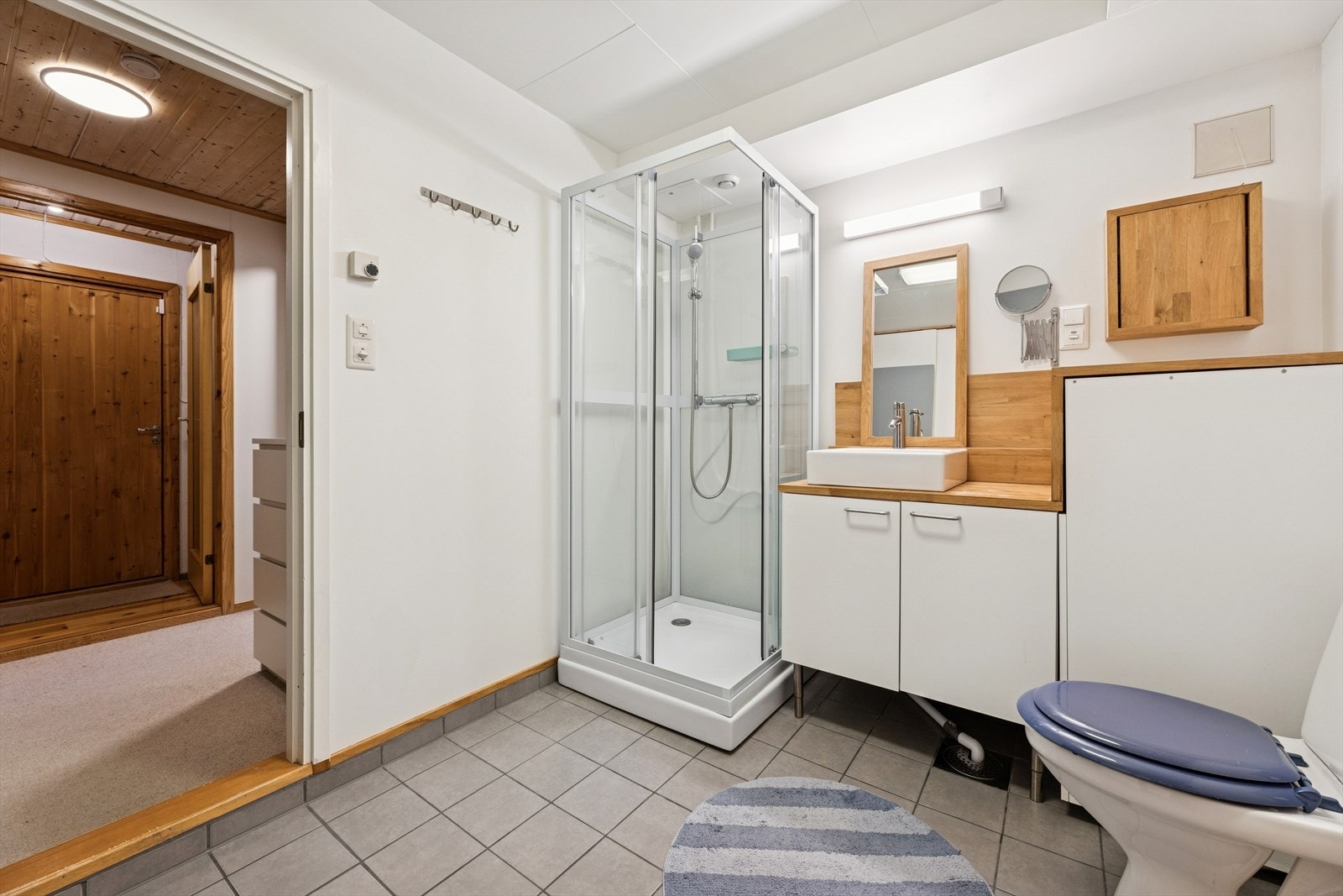 Badet er innredet med baderomsinnredning og benkeplate med servant, dusjkabinett og gulvmontert toalett. Galleribilde