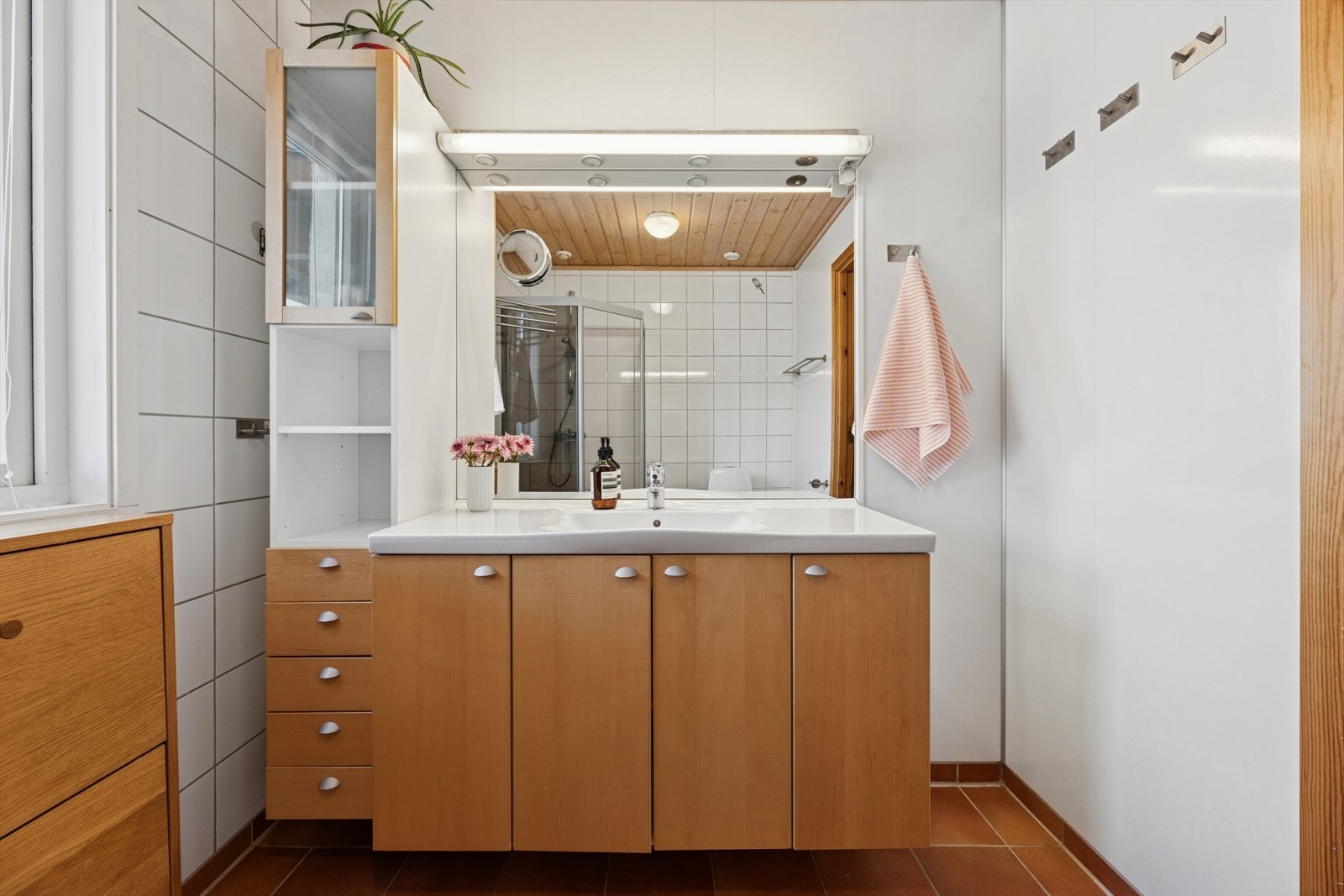 Pen baderomsinnredning og heldekkende servantplate, speil med tilhørende belysning og høyskap. Galleribilde