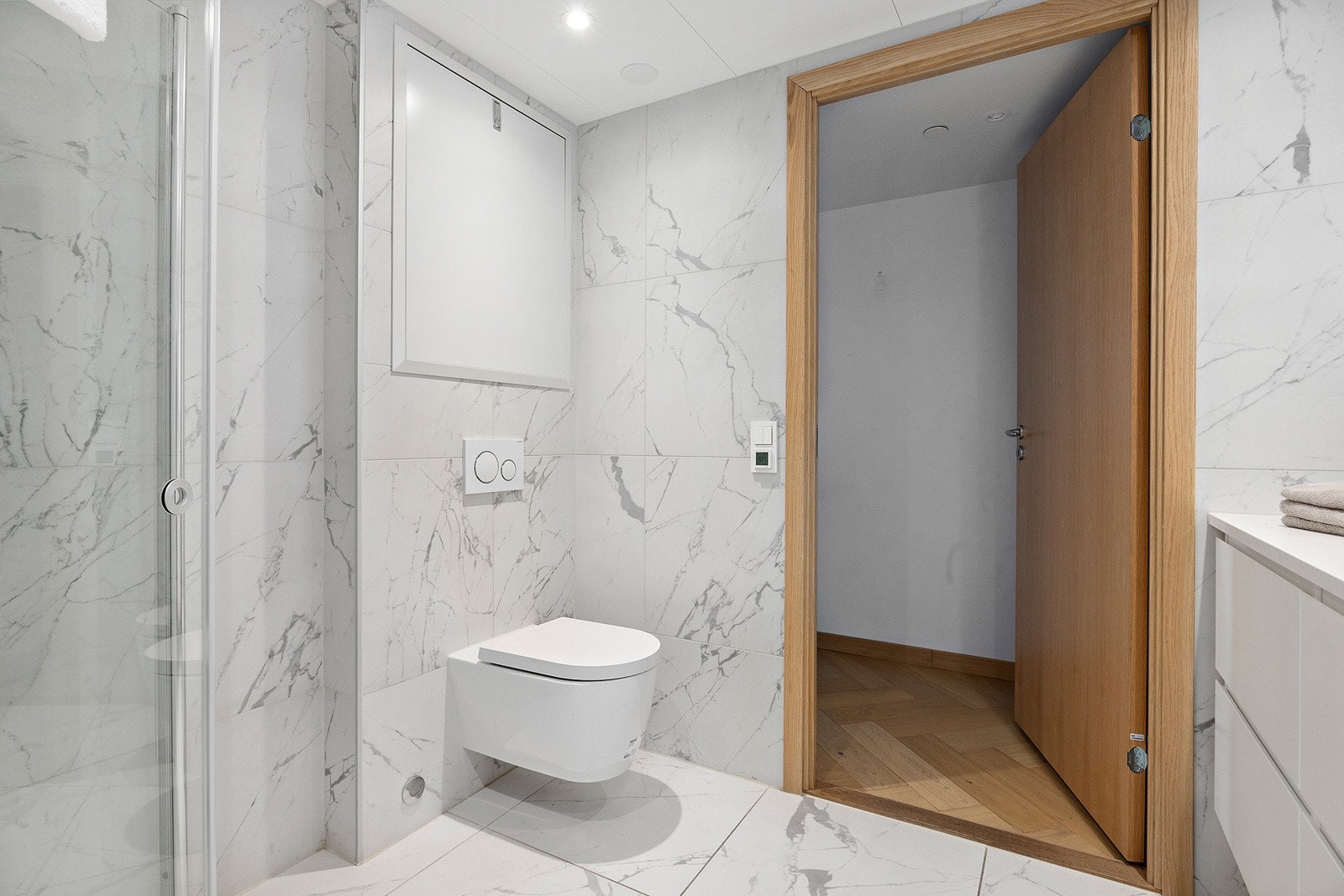 Badet har innredning med servantskap, veggmontert toalett og dusjvegger/hjørne. Galleribilde