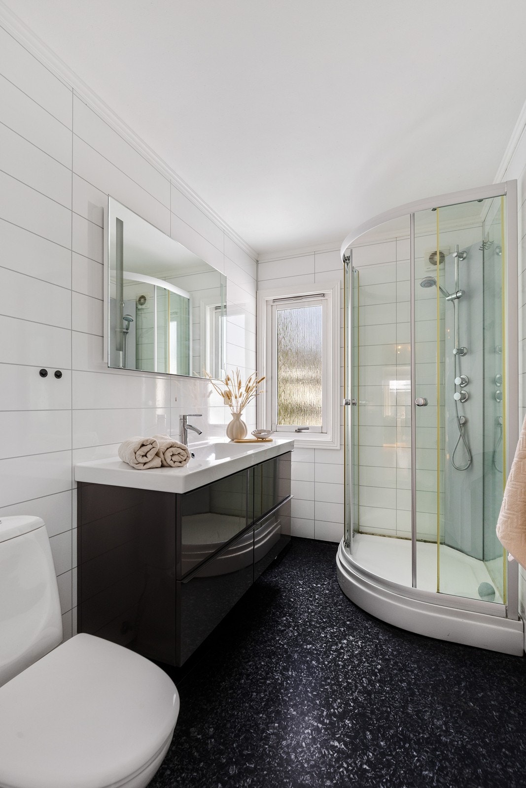 Lyst og moderne bad med servant og underskap, toalett og dusjkabinett . Galleribilde