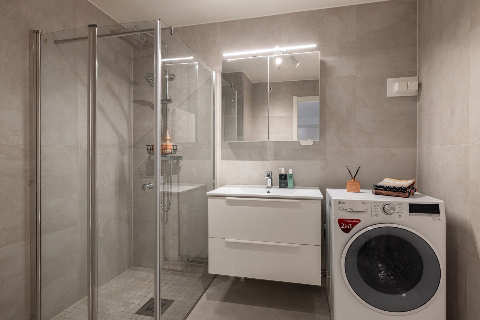 Moderne baderomsinnredning med skuffer og heldekkende servant, speilskap med belysning over. Galleribilde