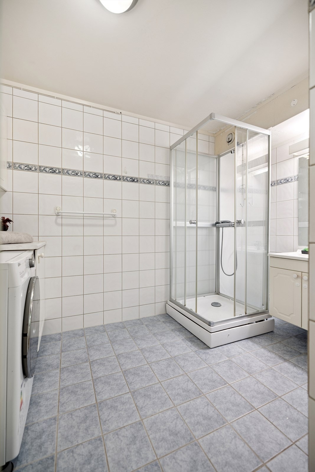 Flislagt bad med dusjkabinett og praktisk opplegg for vaskemaskin. Galleribilde