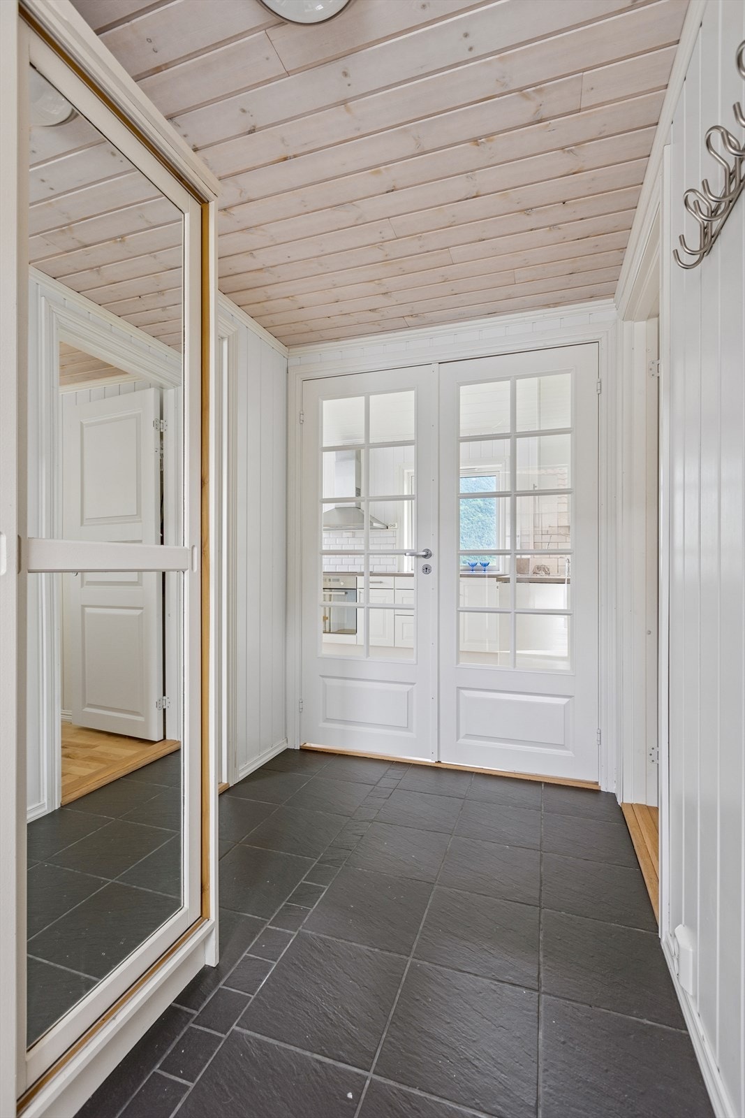 De doble glassdørene gir godt lysinnslipp til inngangspartiet. Det er flislagt gulv i gangen og skyvedørsgarderobe med speil. Her får du deilige varmekabler i gulvet. Galleribilde