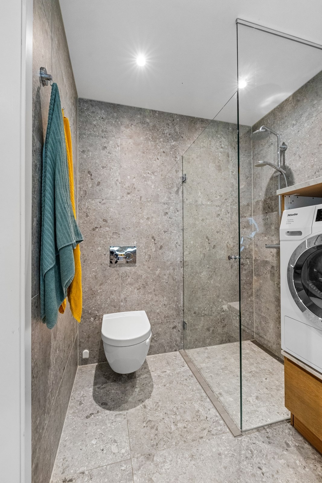 Dusjnisje med innfellbare glassdør, og vegghengt toalett med innebygget sisterne. Galleribilde