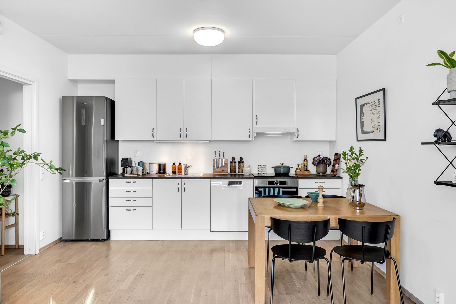 Lekkert kjøkken med glatte fronter, benkeplate i laminat og malt vegg over kjøkkenbenk. Galleribilde