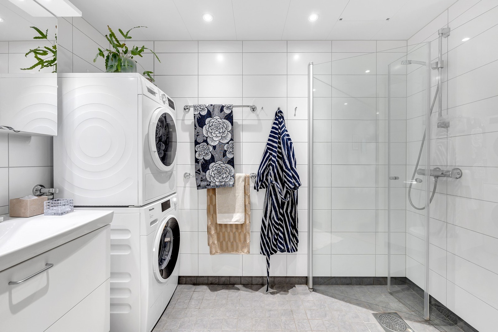 Pent,flislagt bad med opplegg for vaskemaskin og tørketrommel. Vegghengte dusjdører i glass. Galleribilde