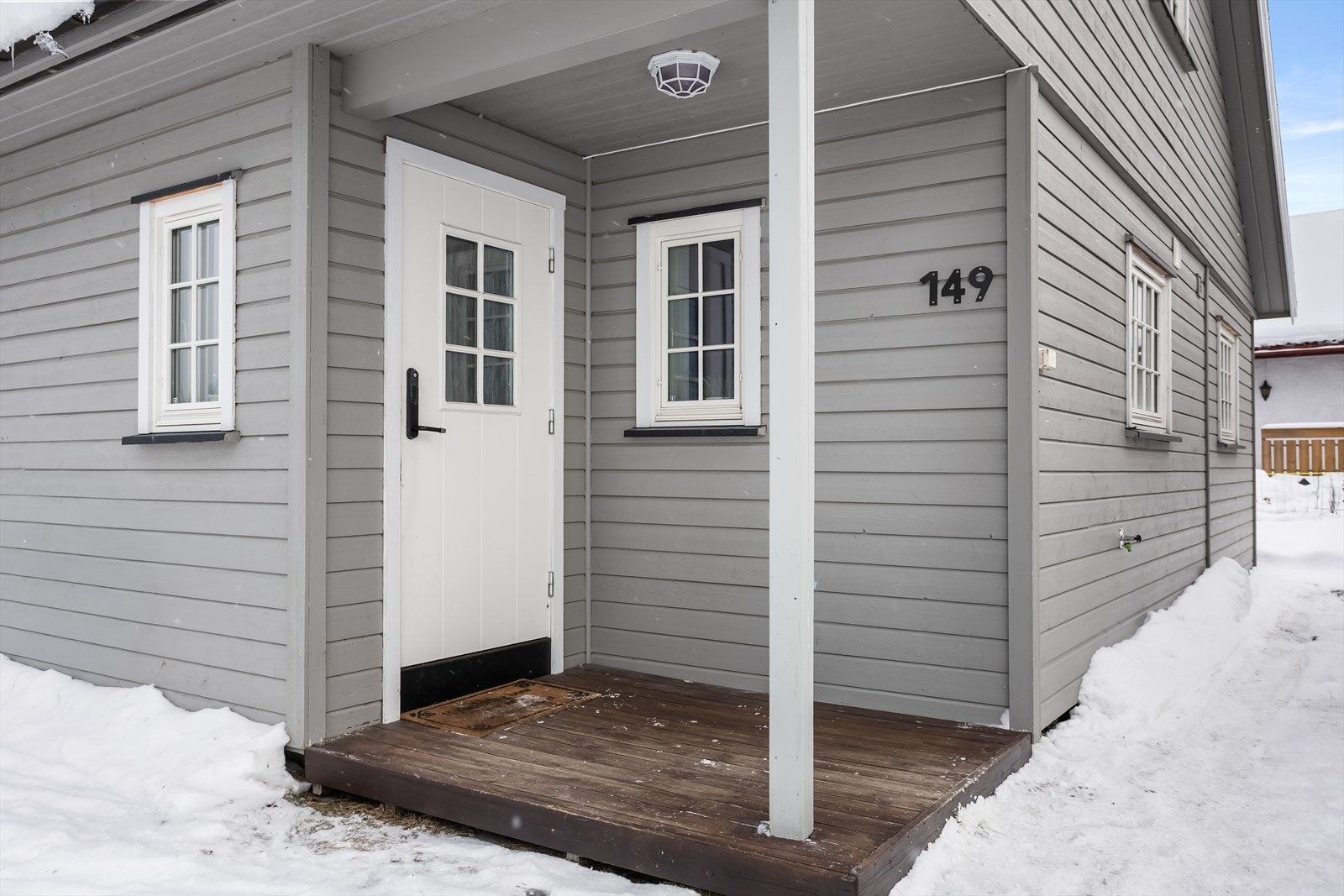 Inngangspartiet har overbygd tak og lyskilde. Parkering skjer i egen garasje på 28 m² og ellers på grusbelagt tomt. Galleribilde