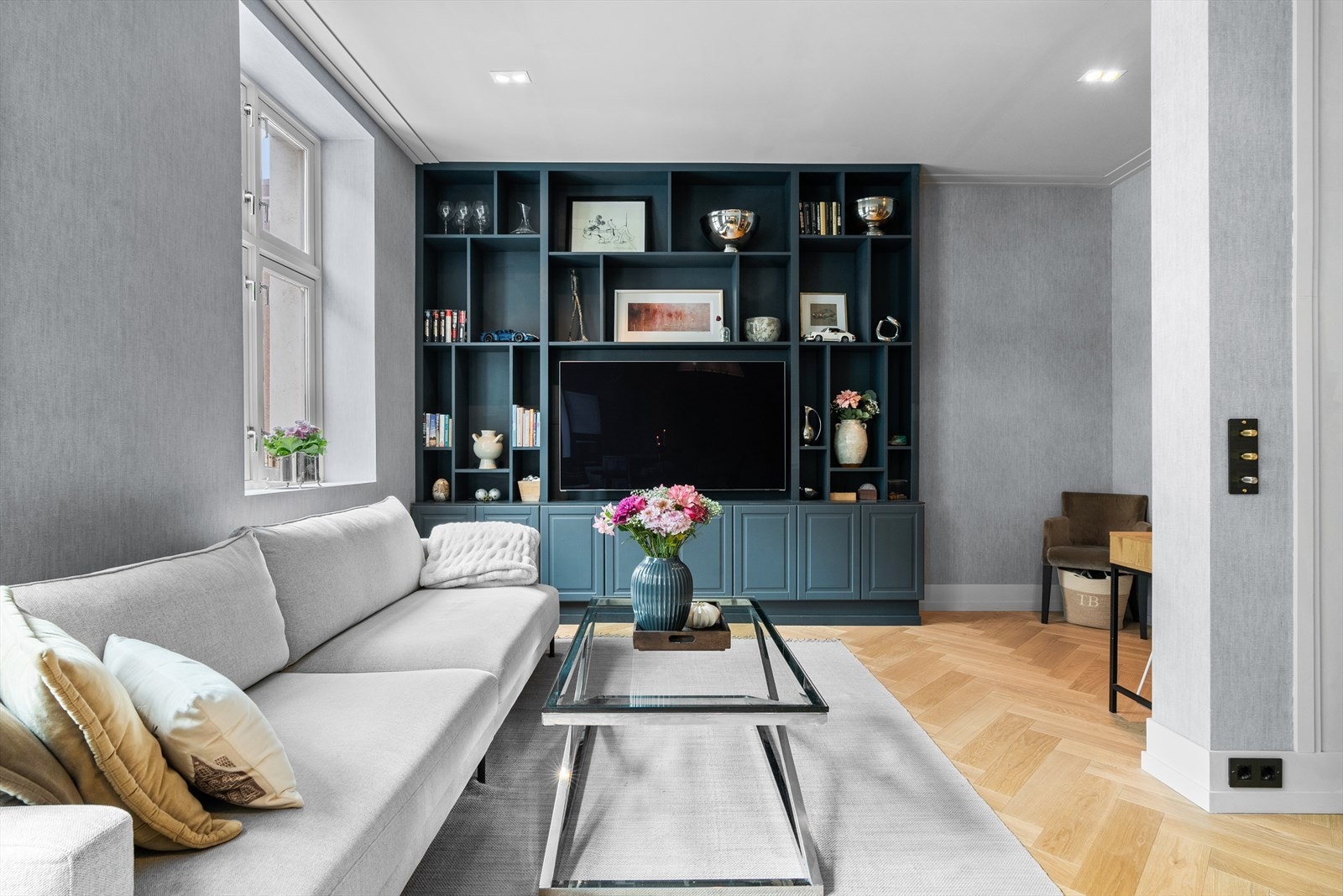 Den plassbygde reolen danner et naturlig midtpunkt i stuen og gir både rikelig oppbevaring og et eksklusivt, møbeltilpasset uttrykk. Galleribilde