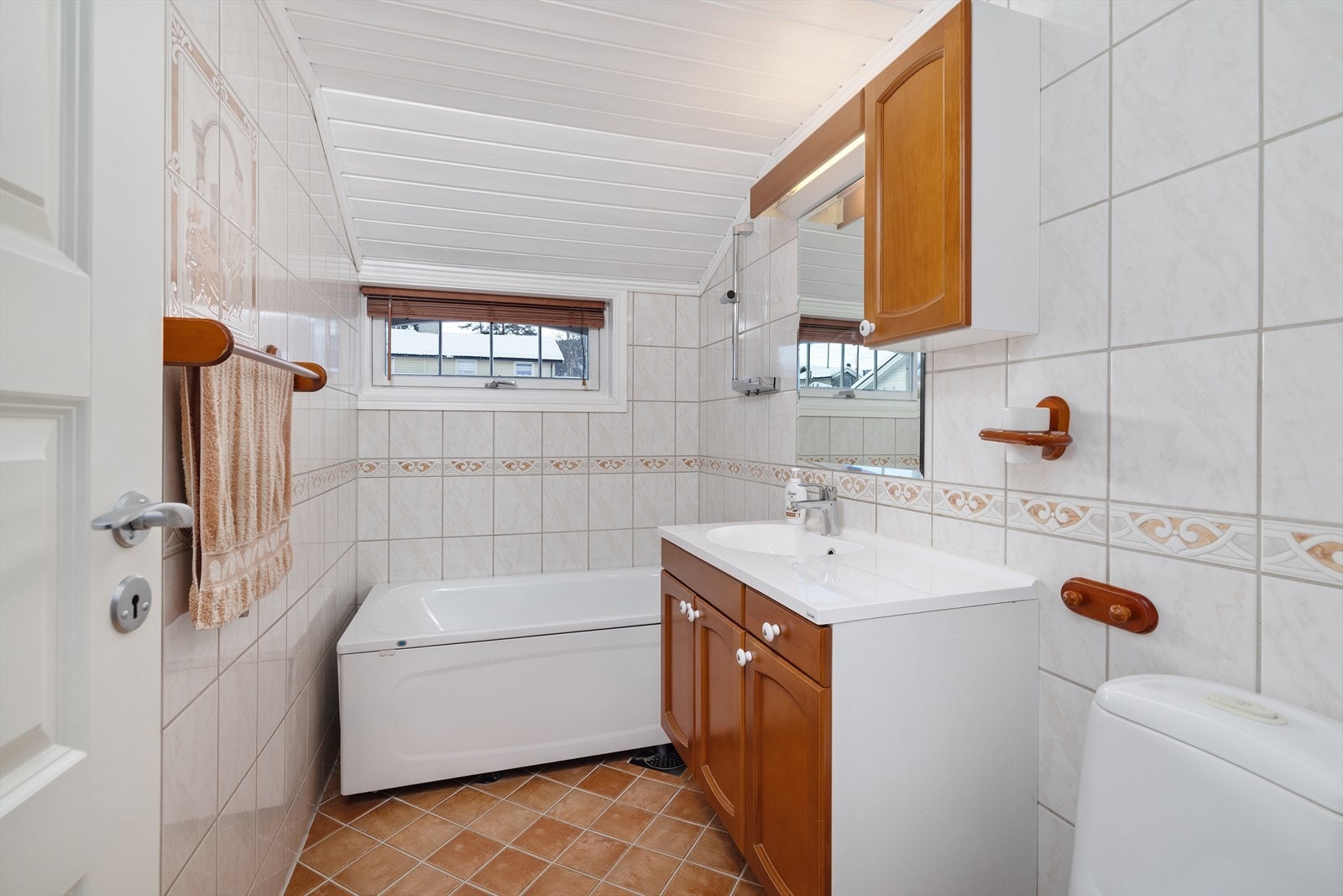 Badet i 1. etasje er flislagt og har elektrisk gulvvarme. Rommet er utstyrt med servantinnredning med ny servantplate og blandebatteri, toalett og badekar med dusj. Galleribilde