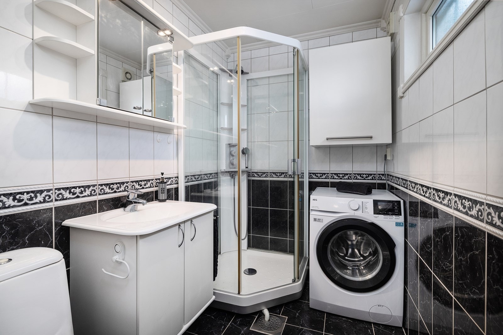 Denne etasjen har et flislagt bad som inkluderer innredning med servant, lukket dusjkabinett og frittstående toalett, samt opplegg for vaskemaskin. Galleribilde