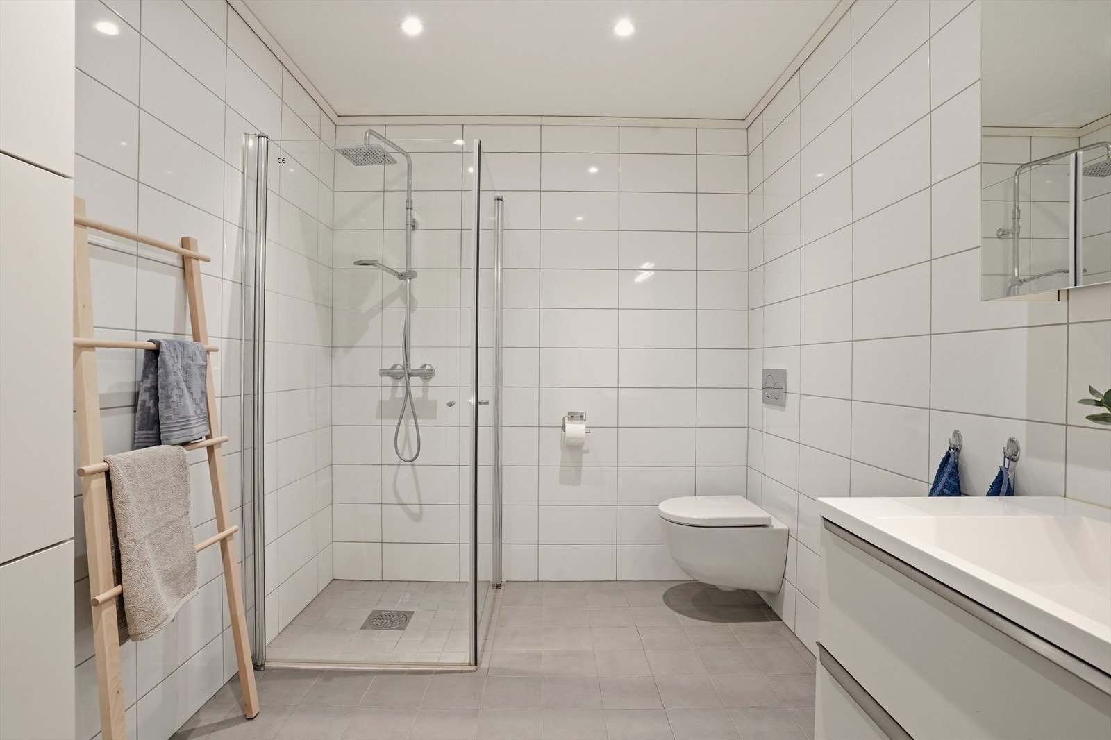 Badet er innredet med servantskap med nedfelt servant, vegghengt toalett og dusjvegger/hjørne. Galleribilde