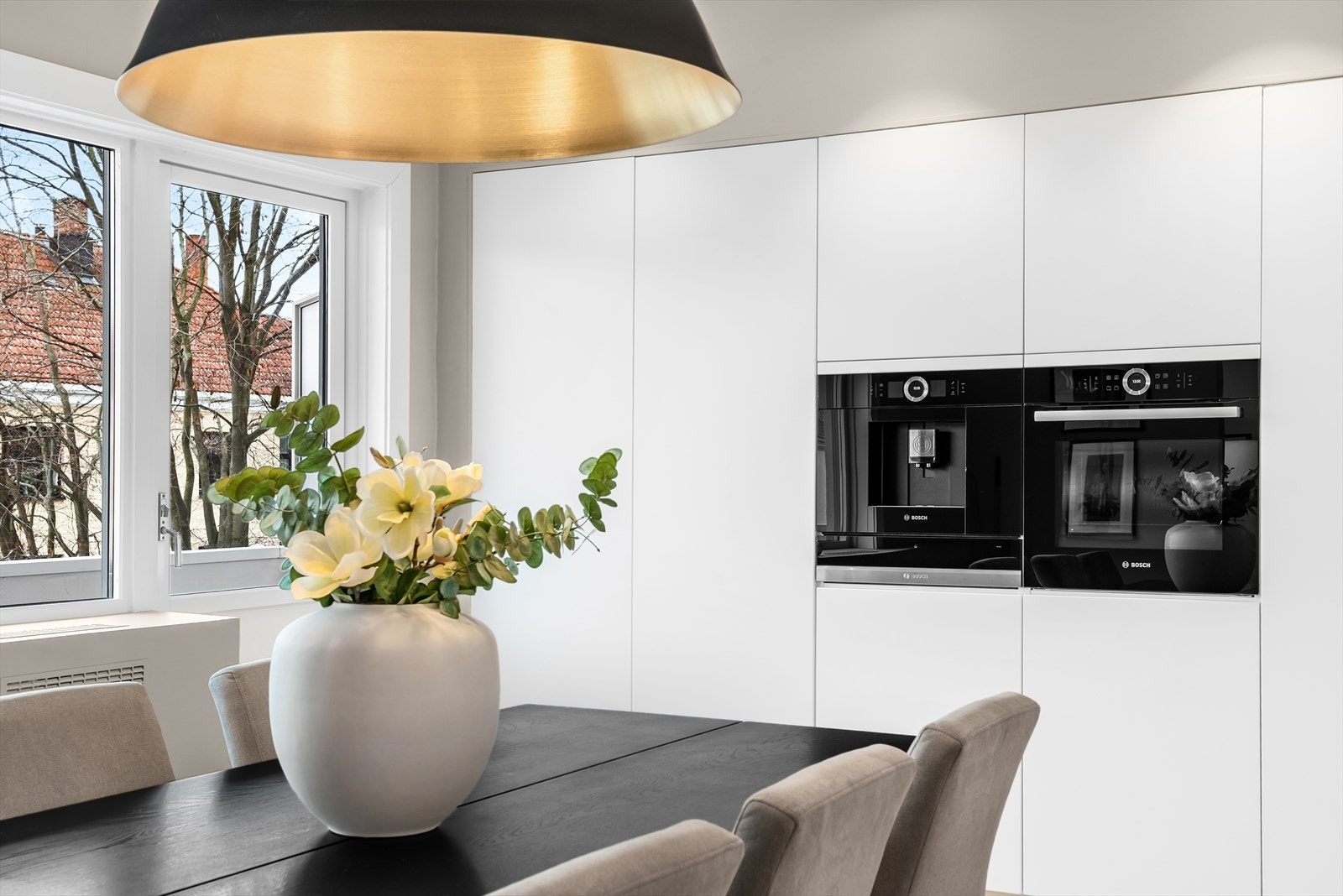 Veggen med høyskap inneholder høyskap med lagring, integrert fullsize fryseskap, kaffemaskin, varmeskuff, stekeovn, fullsize kjøleskap samt enda et høyskap med lagring. Galleribilde