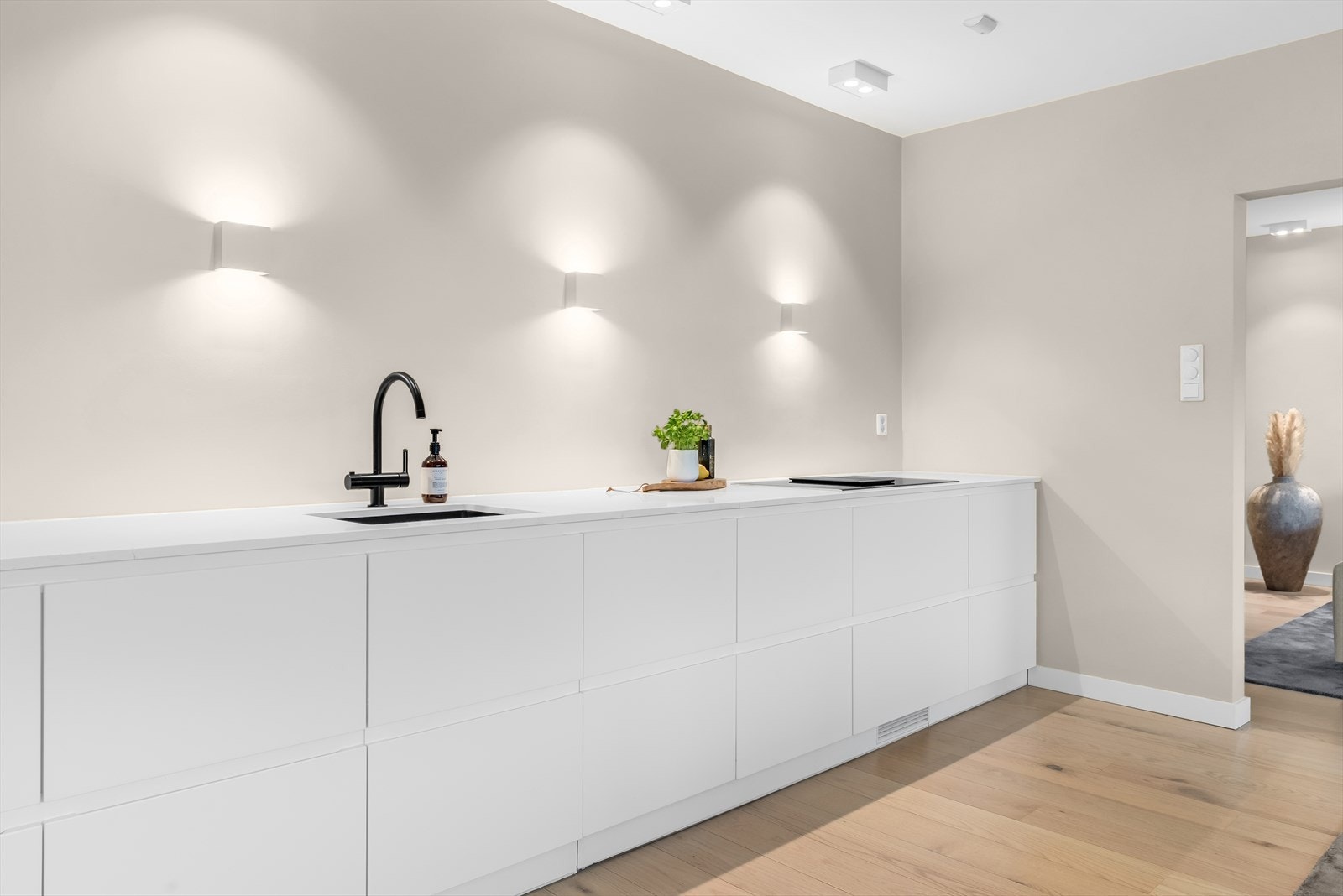 Moderne integrert led-belysning med skjult elektrisk anlegg. God benkeplass med stilig sort Tapwell armatur og underlimt oppvaskkum fra Blanco, samt induksjonstopp fra Bosch på 80 cm med fleksible varmeflater og integrert omluftsventilator. Galleribilde