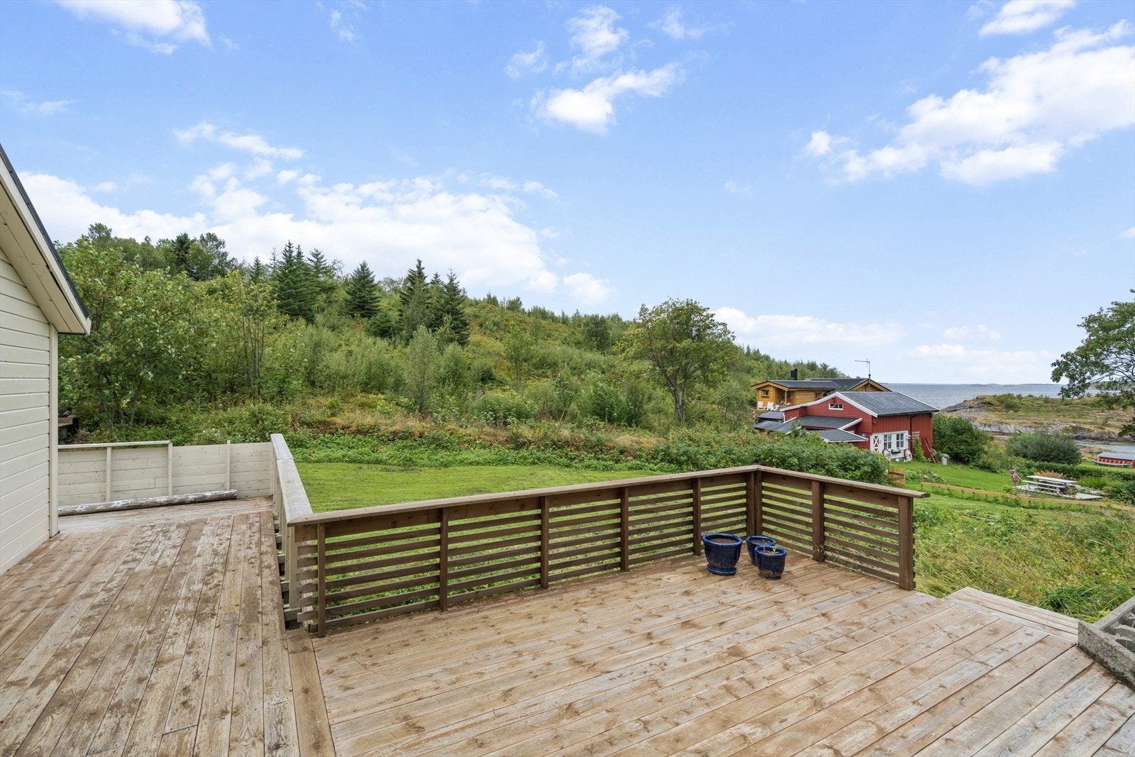 Deler av terrasse med utsikt ned mot naust og havet Galleribilde