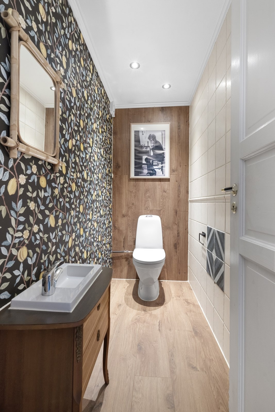 Inntil badet er det eget toalettrom med laminatgulv og spennende innslag av både flis, tapet og laminat på veggene. Her er det innredning med nedfelt servant. Down-light belysning i tak. Galleribilde