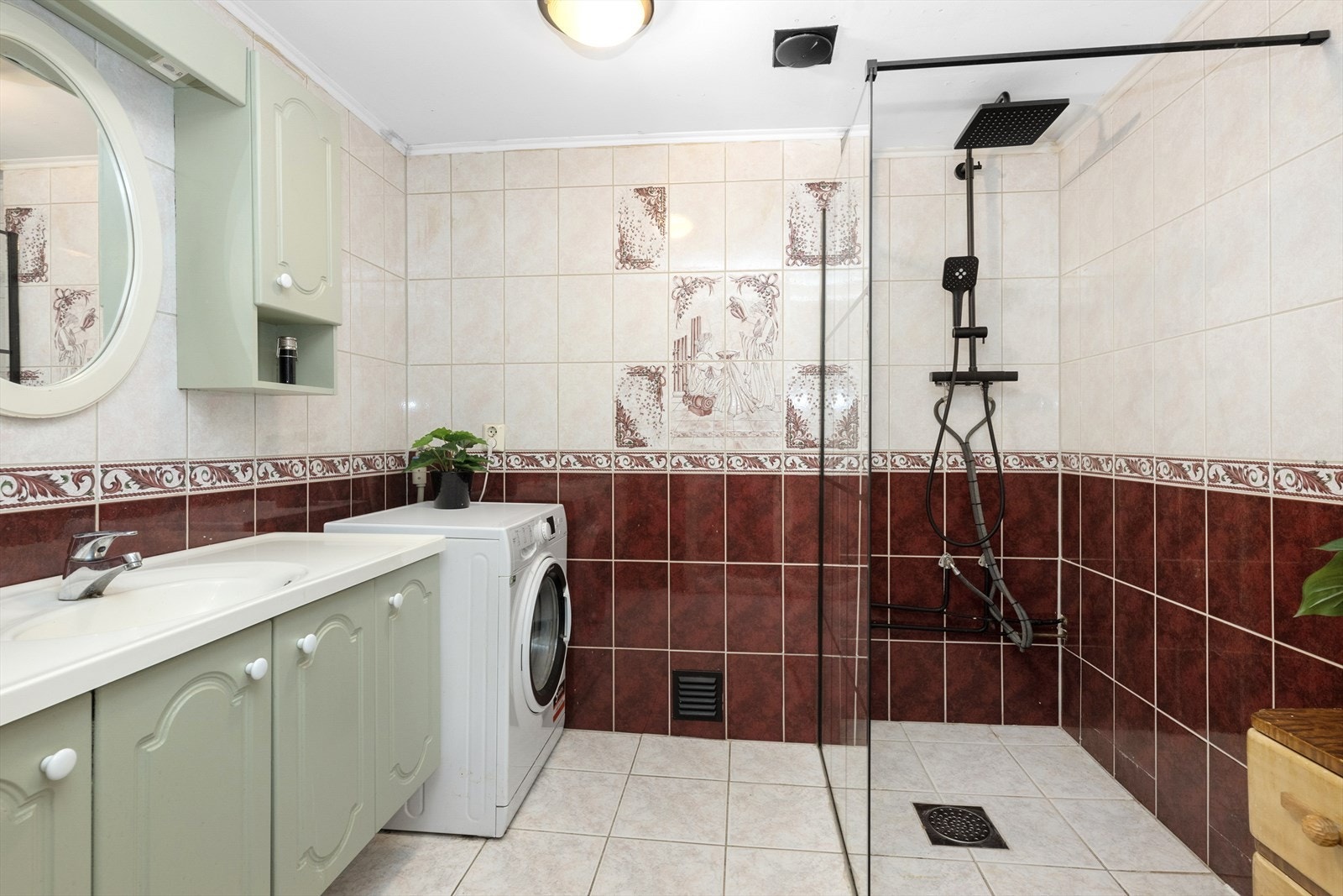 Badet er helfliset og har god oppbevaringsplass i innredning med heldekkende servant og overskap. Det er glassvegg inn mot dusjnisjen med sorte profiler, og sort dusjgarnityr med behagelig regnfallsdusj. Badet har også opplegg for og plass til vaskemaskin Galleribilde