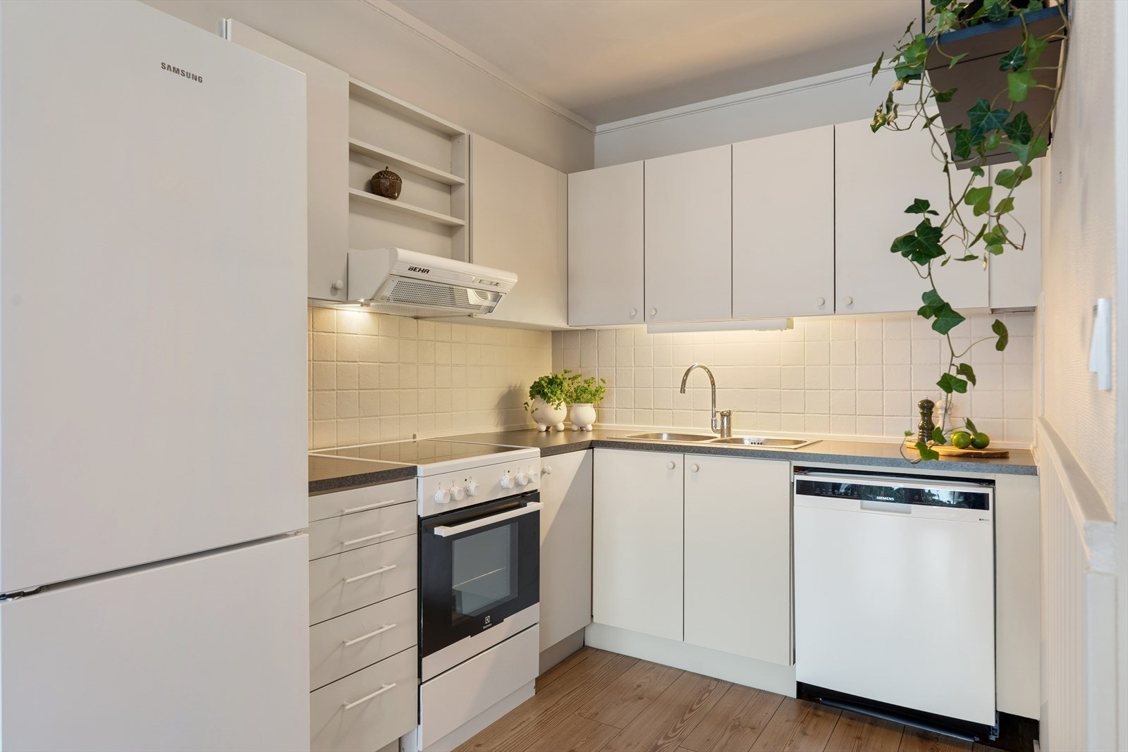 Kjøkkeninnredning med malte, glatte fronter og benkeplate i laminat. Galleribilde