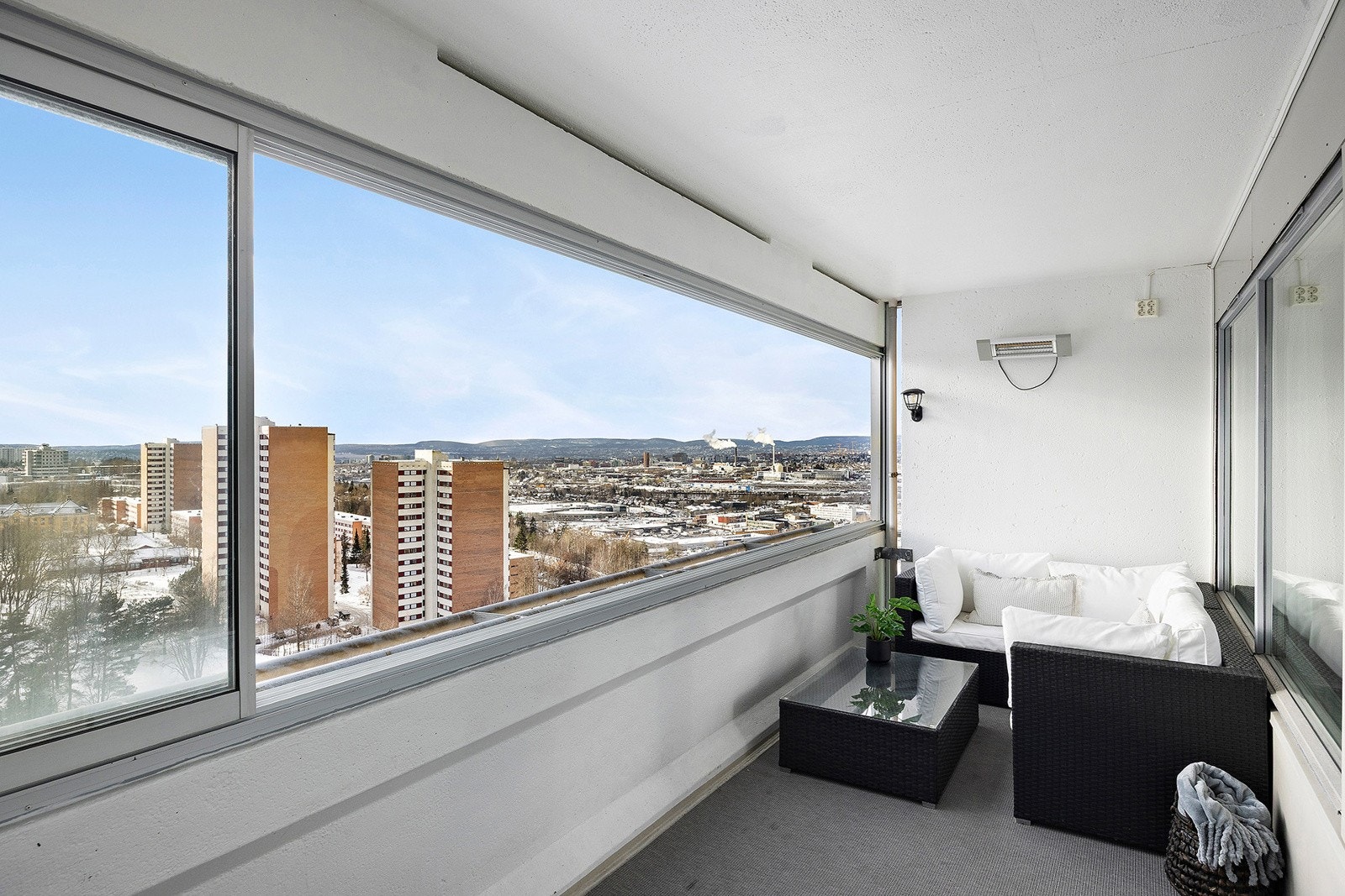 Sydvestvendt innglasset balkong på 10m² med teppe på gulv, belysning, strømuttak, flott utsikt og adkomst fra stue. Galleribilde