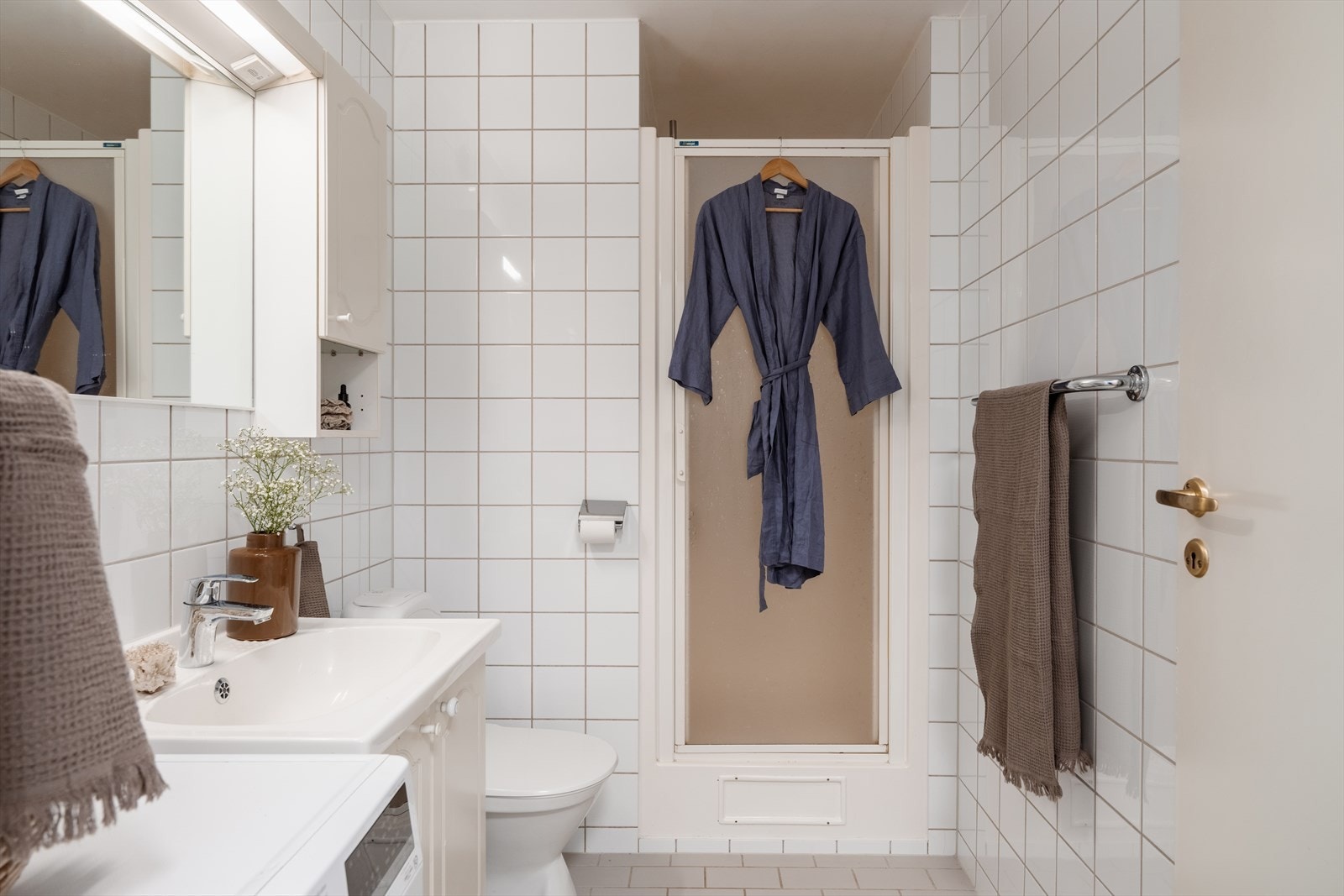 Baderommet er innredet med servant, toalett og dusjhjørne med glassdør Galleribilde