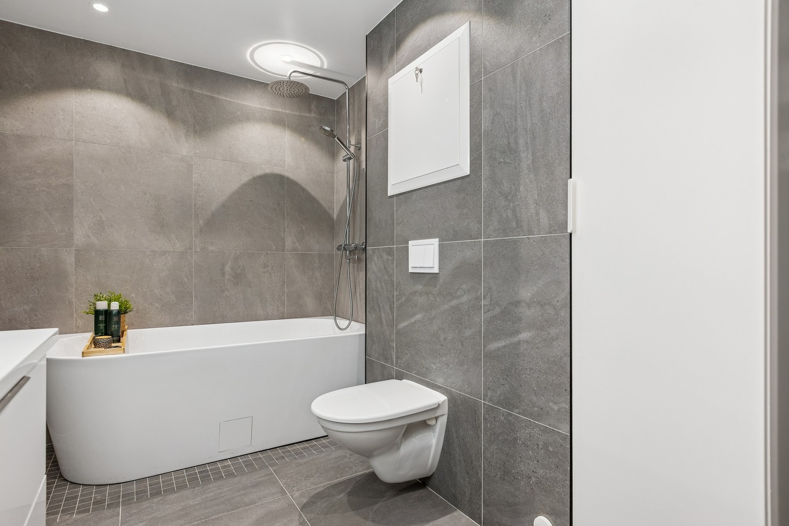 Badet er utstyrt med vegghengt toalett, badekar med regndusj og servantinnredning med speil. Galleribilde