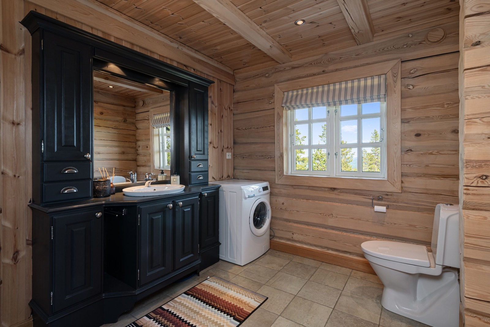 Lunt baderom med flislagt gulv og stilfull innredning. Opplegg for vaskemaskin/tørketrommel. Galleribilde