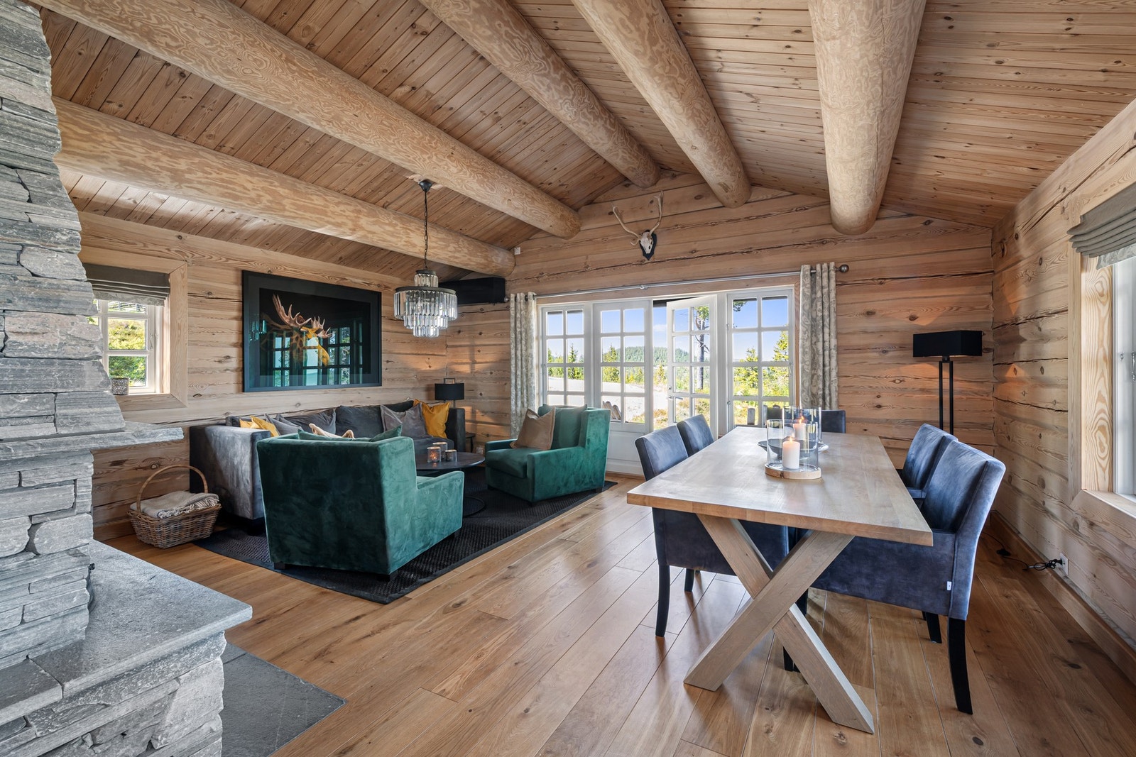 Stor, åpen stue med laftede tømmervegger, god takhøyde og stemningsfull peisovn. Galleribilde