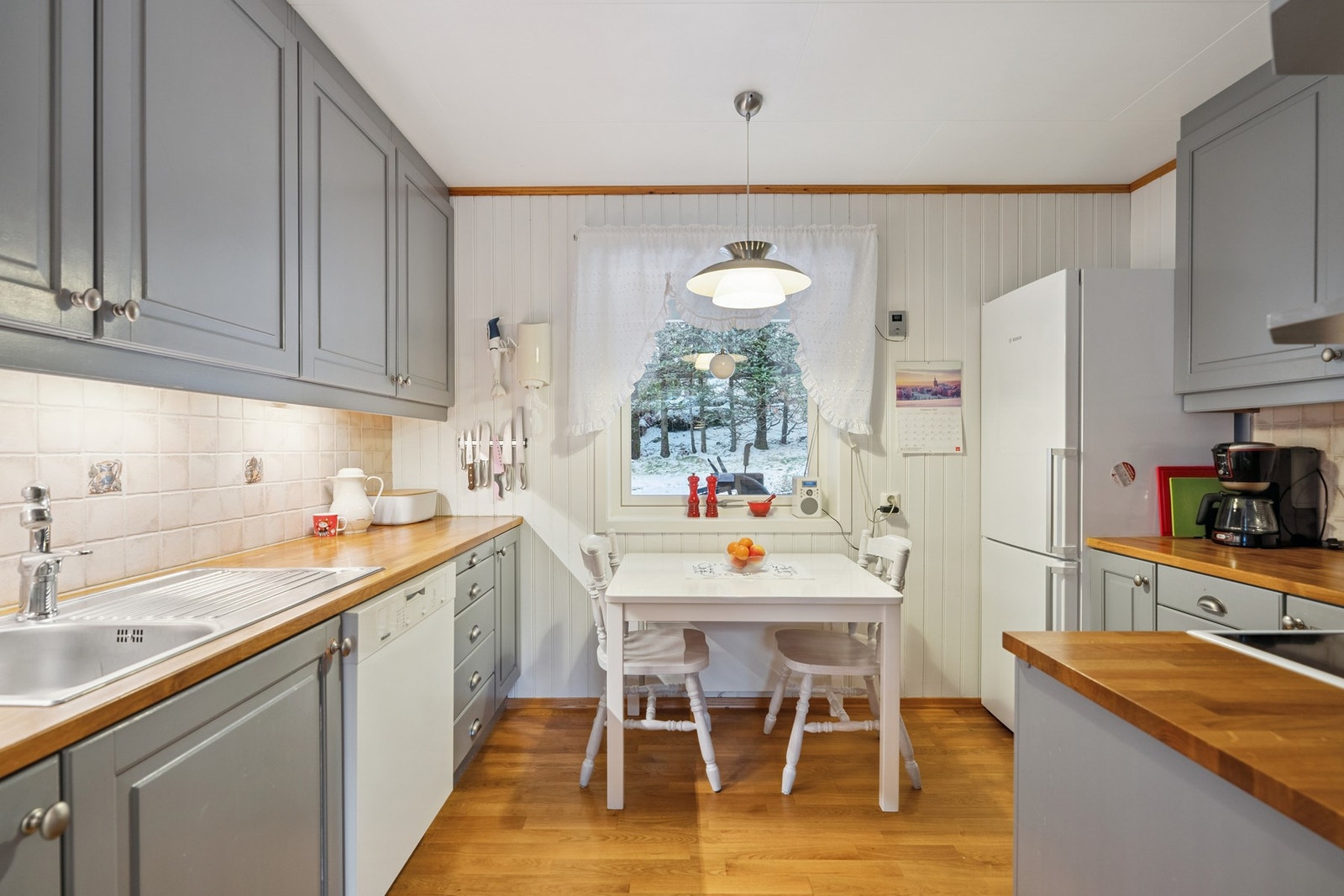 Kjøkken med malte profilerte fronter og benkeplate i heltre. Flislagt mellom benk og overskap, samt ventilator med avtrekk ut. Galleribilde