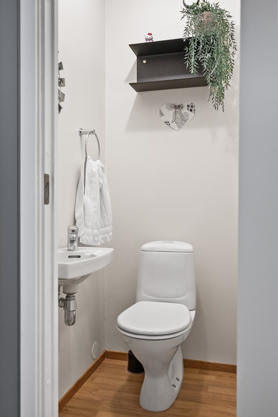 Toalettrom med laminat på gulvet, malt tapet på vegger, og malt slett tak. Rommet er innredet med servant og toalett. Galleribilde