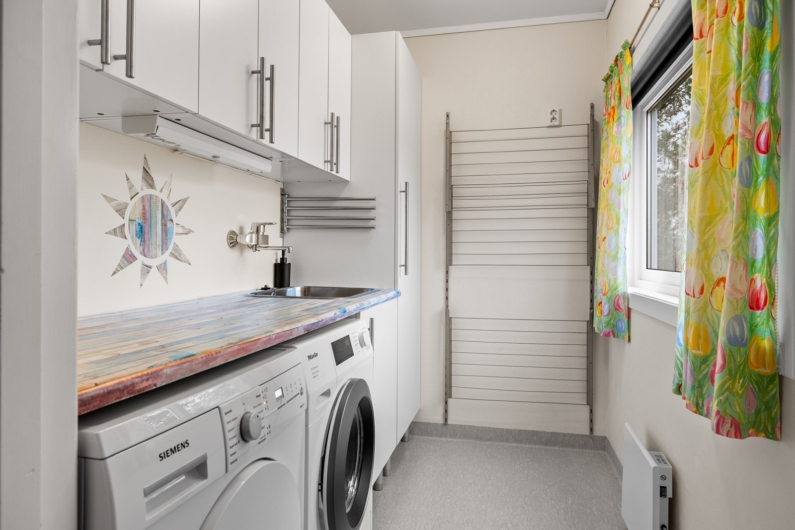 Vaskerommet er praktisk tilrettelagt med utslagsvask og tilhørende skapinnredning som gir gode oppbevaringsmuligheter. Galleribilde