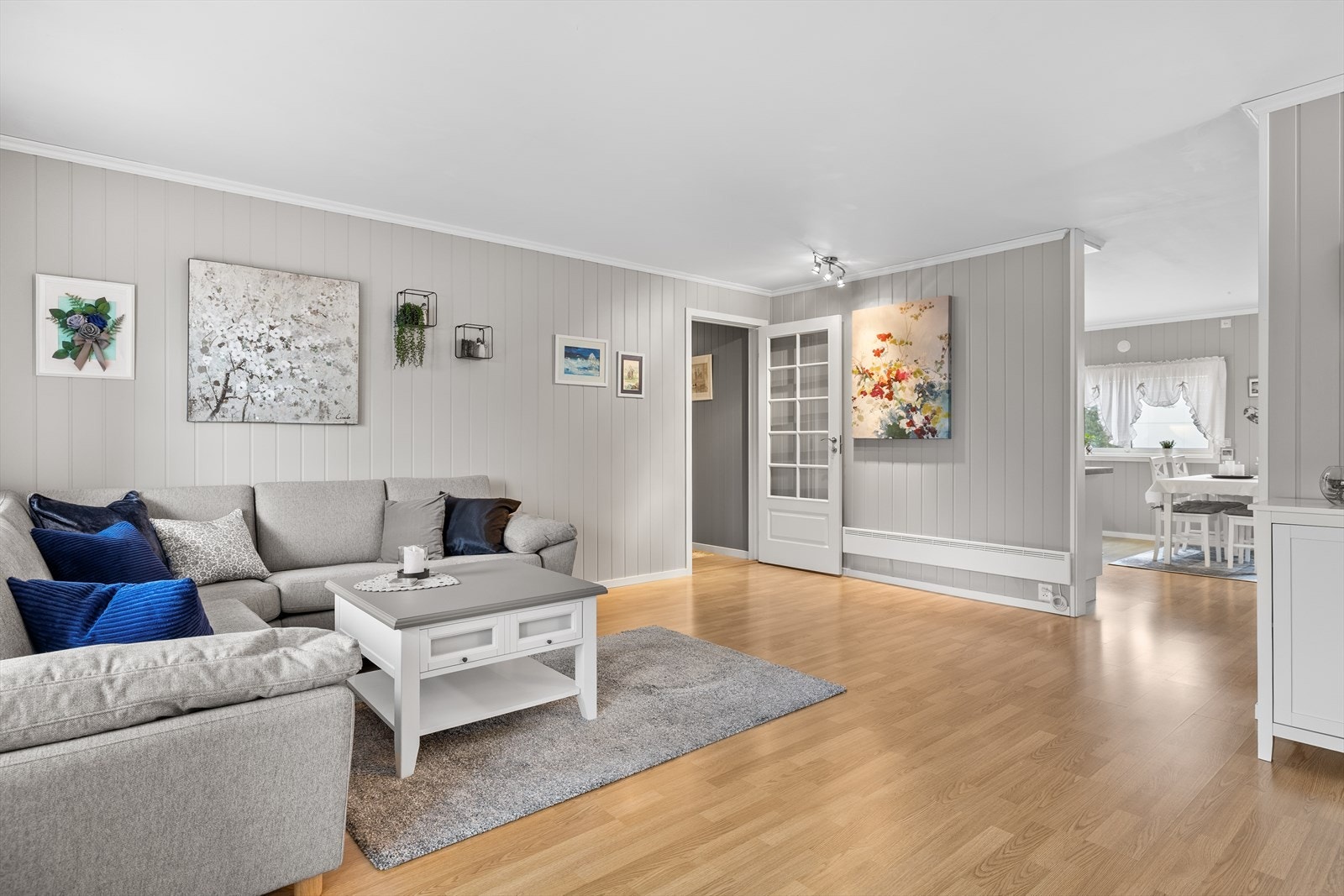 Stuen fremstår som et lyst og behagelig oppholdsrom med laminat på gulv og malte, delikate og tidløse vegger. Rommet har en naturlig og åpen utforming som gjør det enkelt å møblere etter behov og smak. Galleribilde